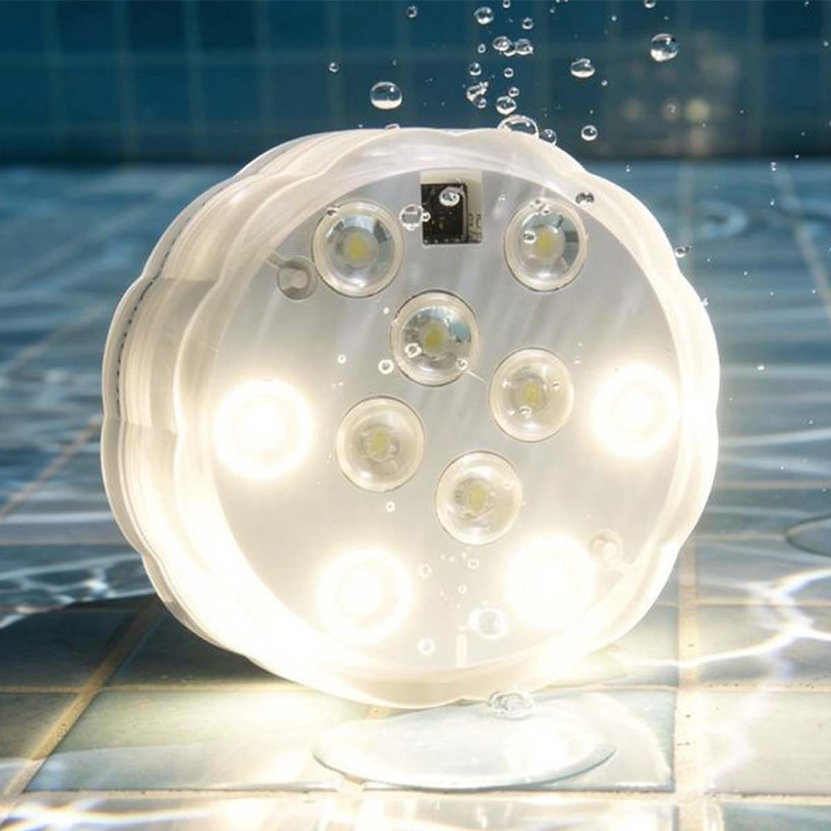 Una luz redonda blanca submarina con muchos LEDs brilla intensamente en una piscina.