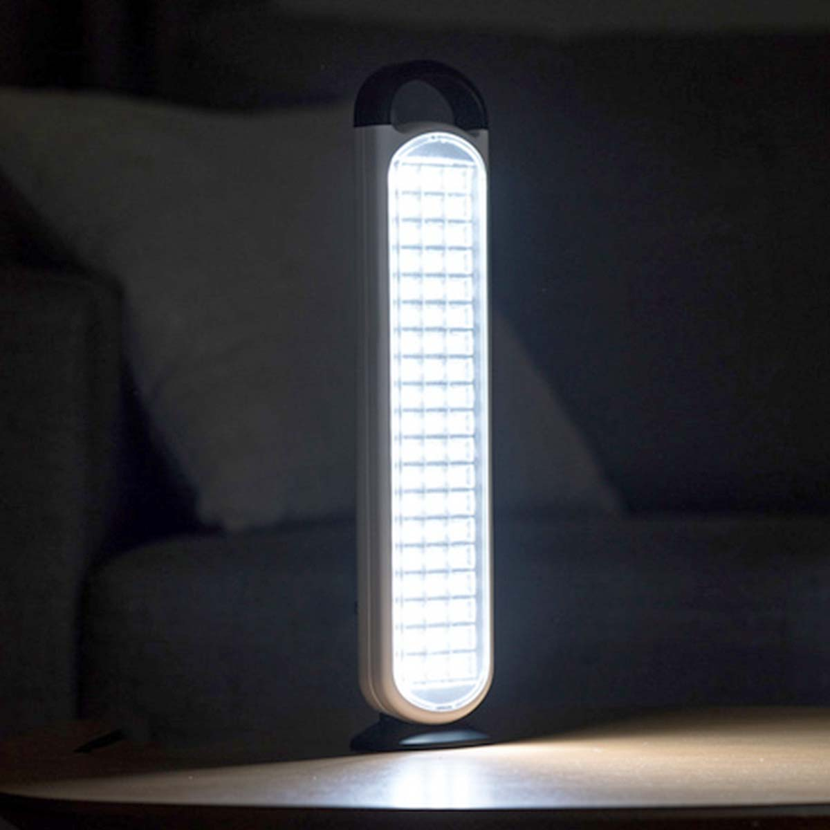 Eine helle LED-Lampe mit Griff steht auf einem Tisch.