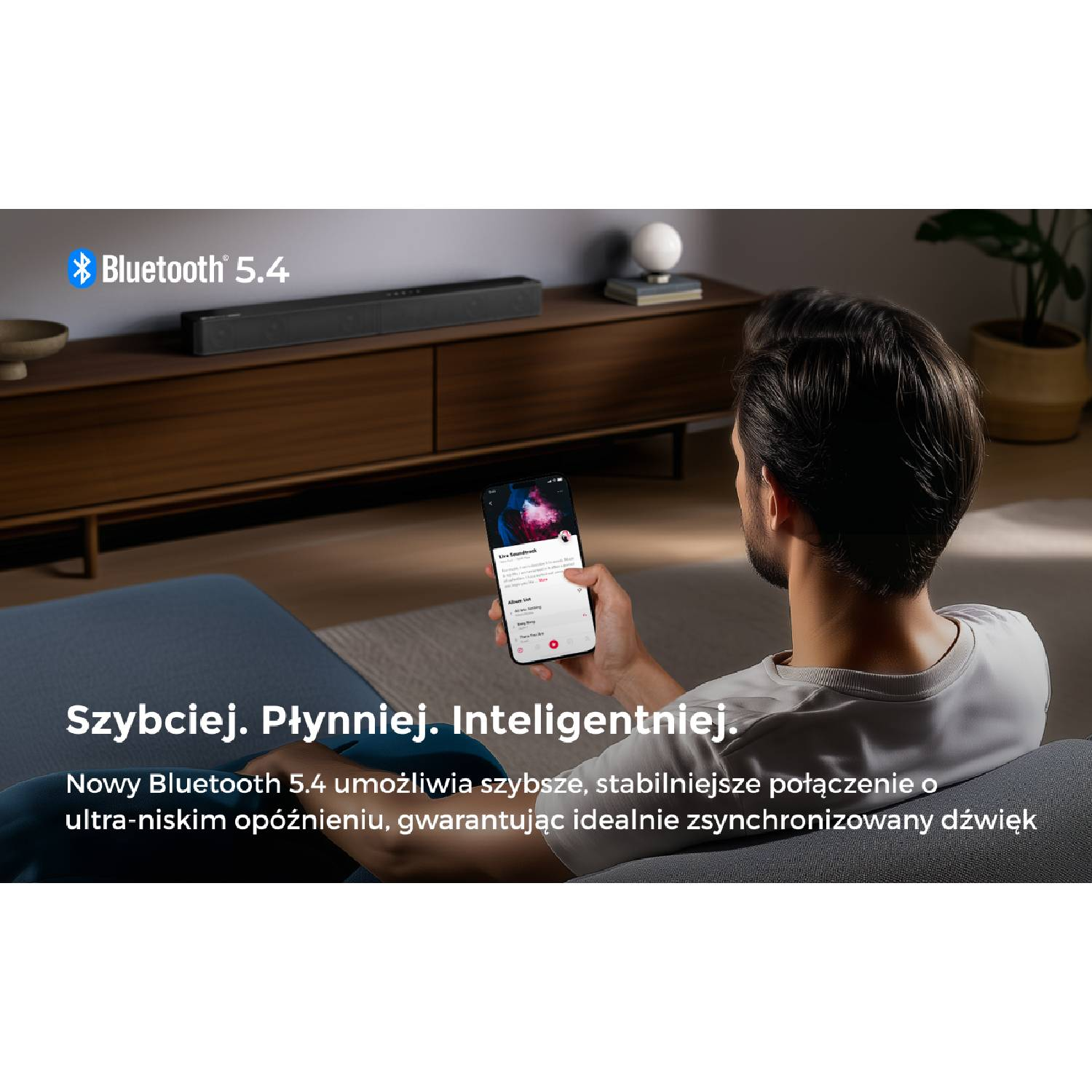 Mężczyzna trzyma smartfon z logo Bluetooth 5.4, soundbar w tle.