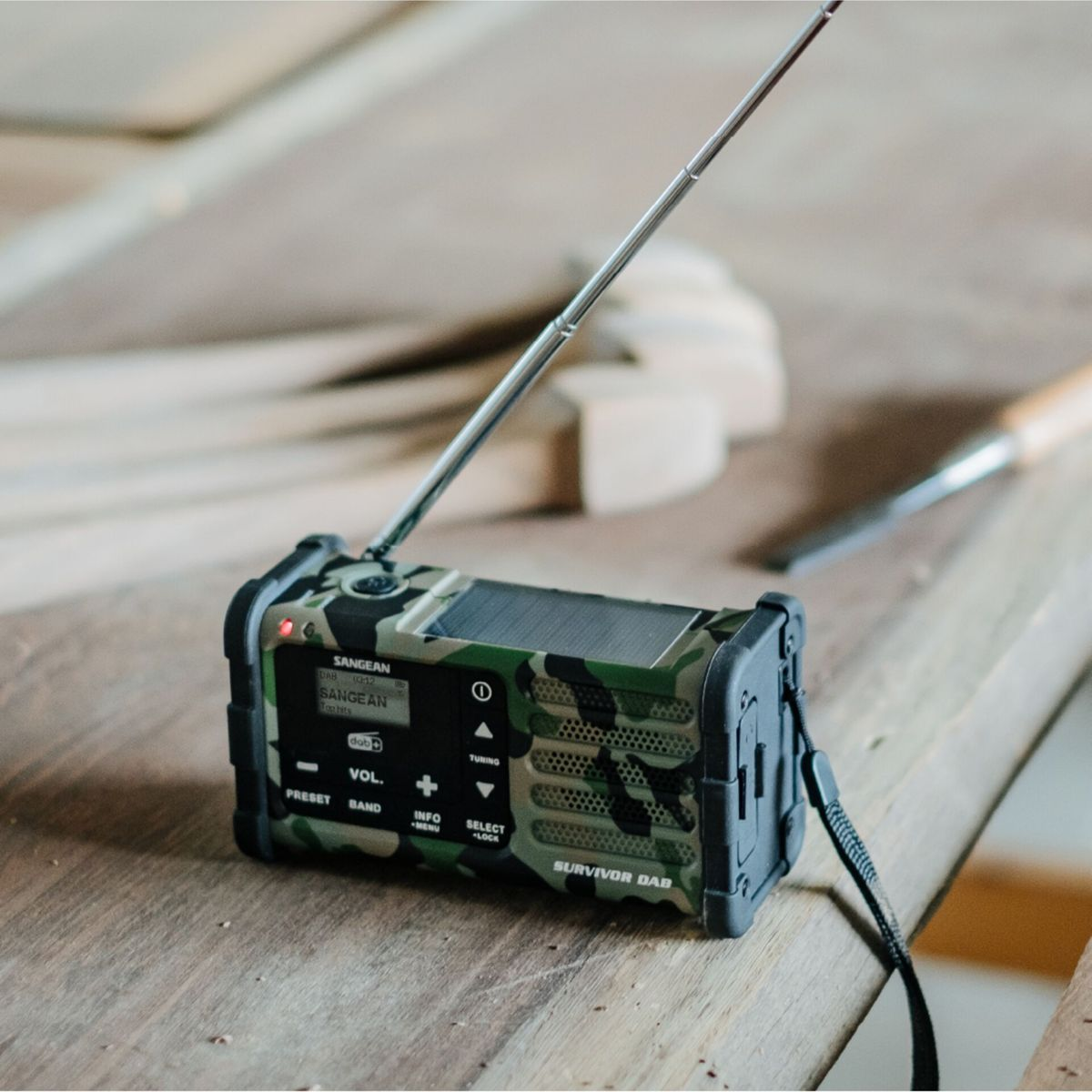 Una radio Sangean Survivor DAB con motivo mimetico su un tavolo di legno.