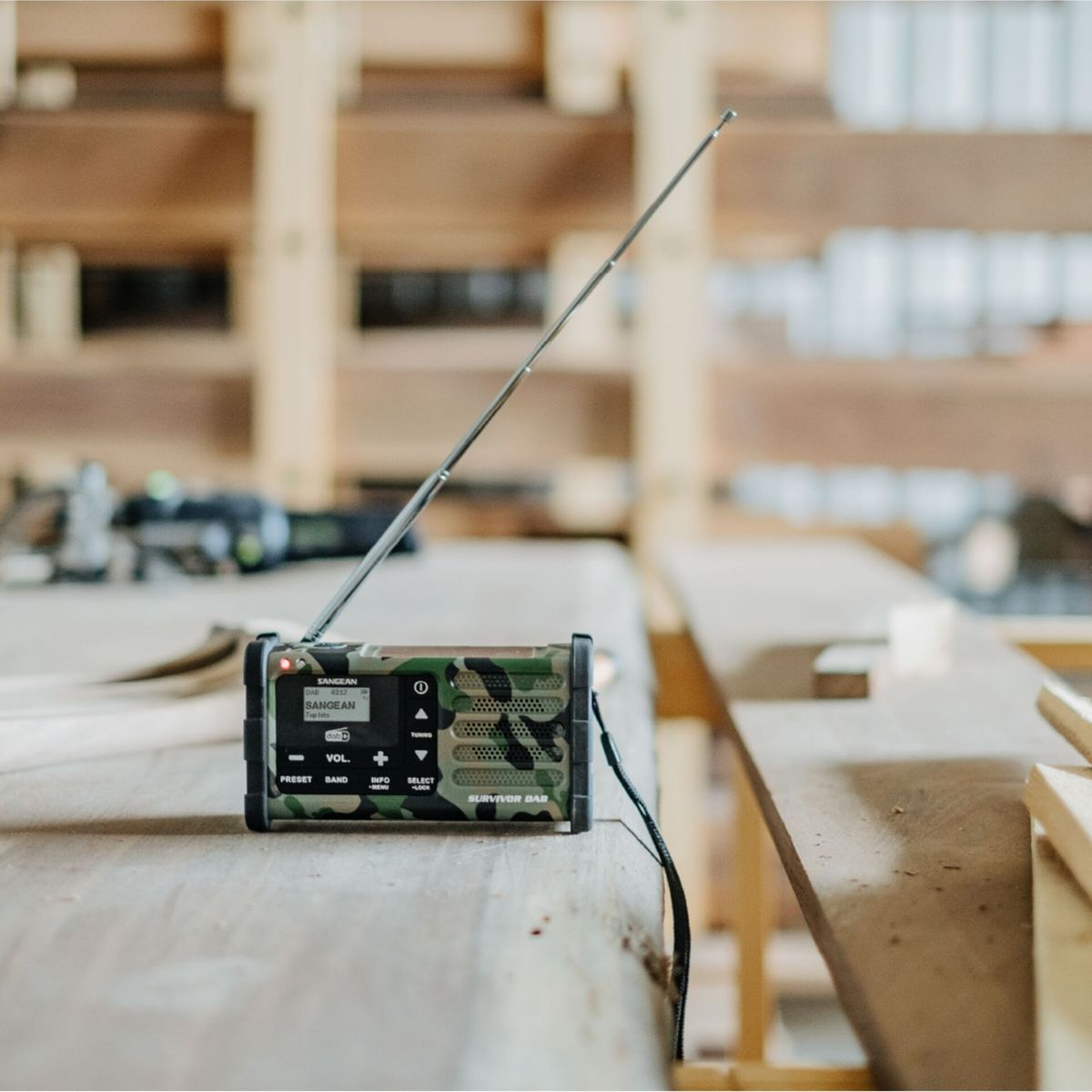 Una radio DAB mimetica con antenna estesa su una superficie di legno.