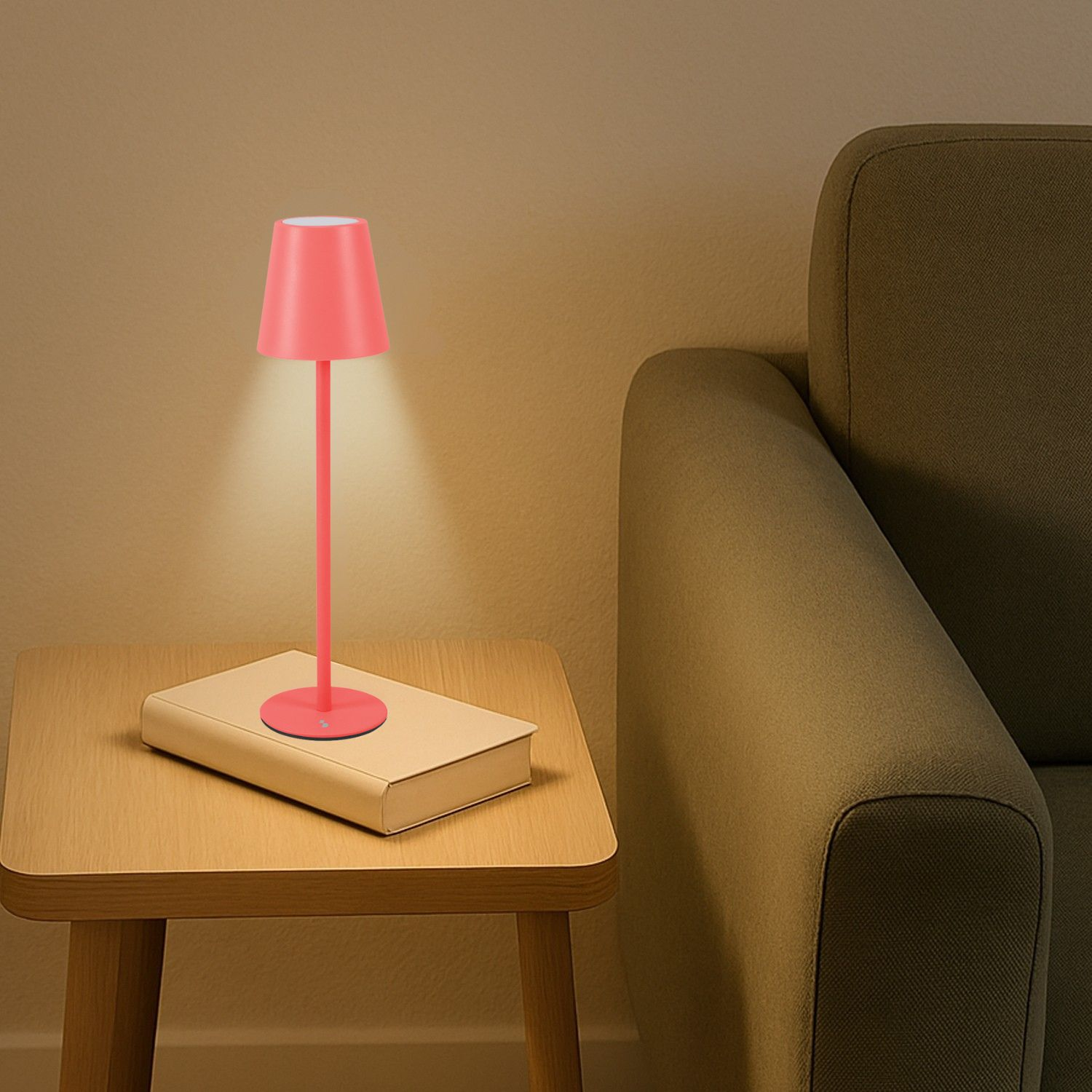 Una lampada rosa è su un libro accanto a un divano.