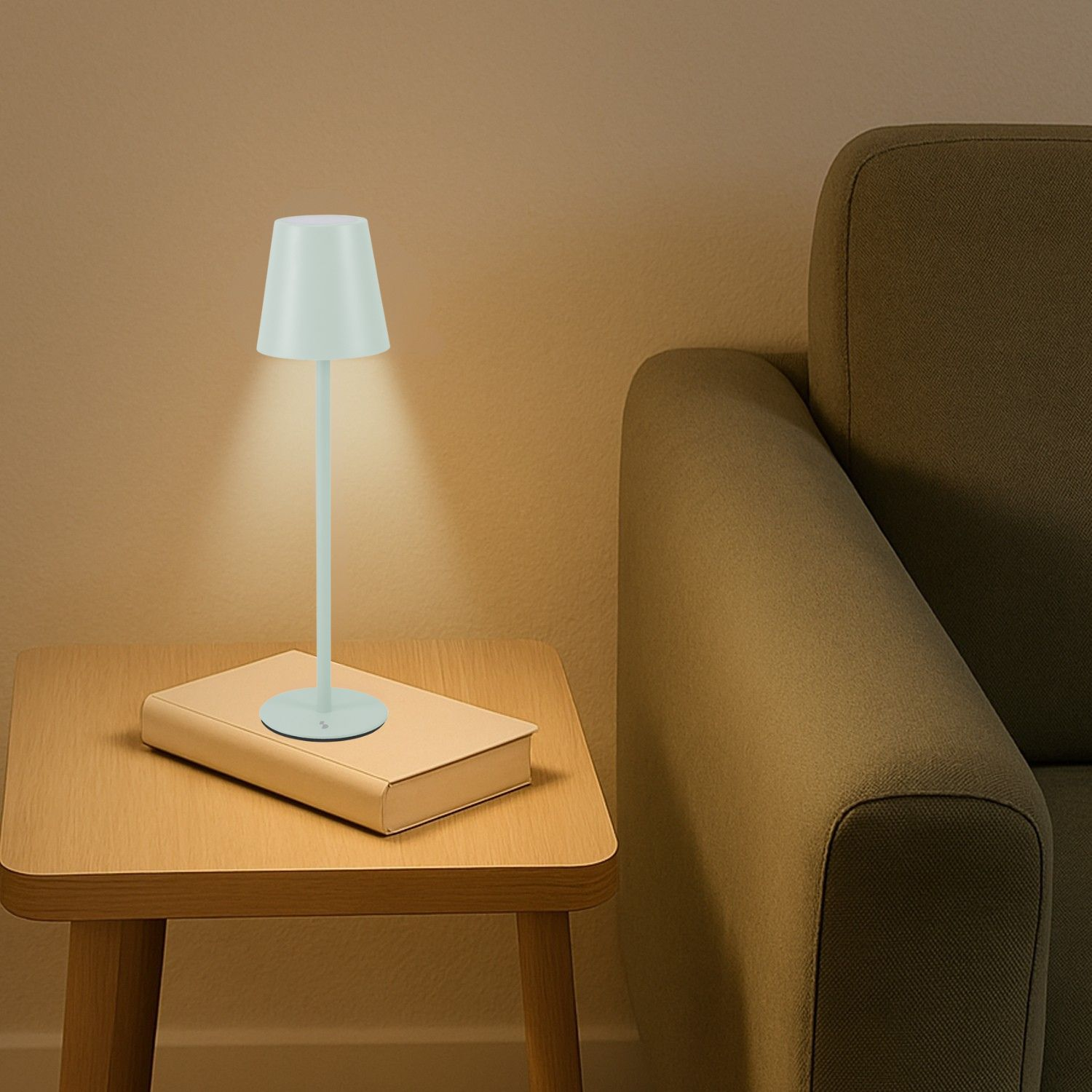 Una lampada bianca illumina un libro su un tavolo di legno accanto a un divano.