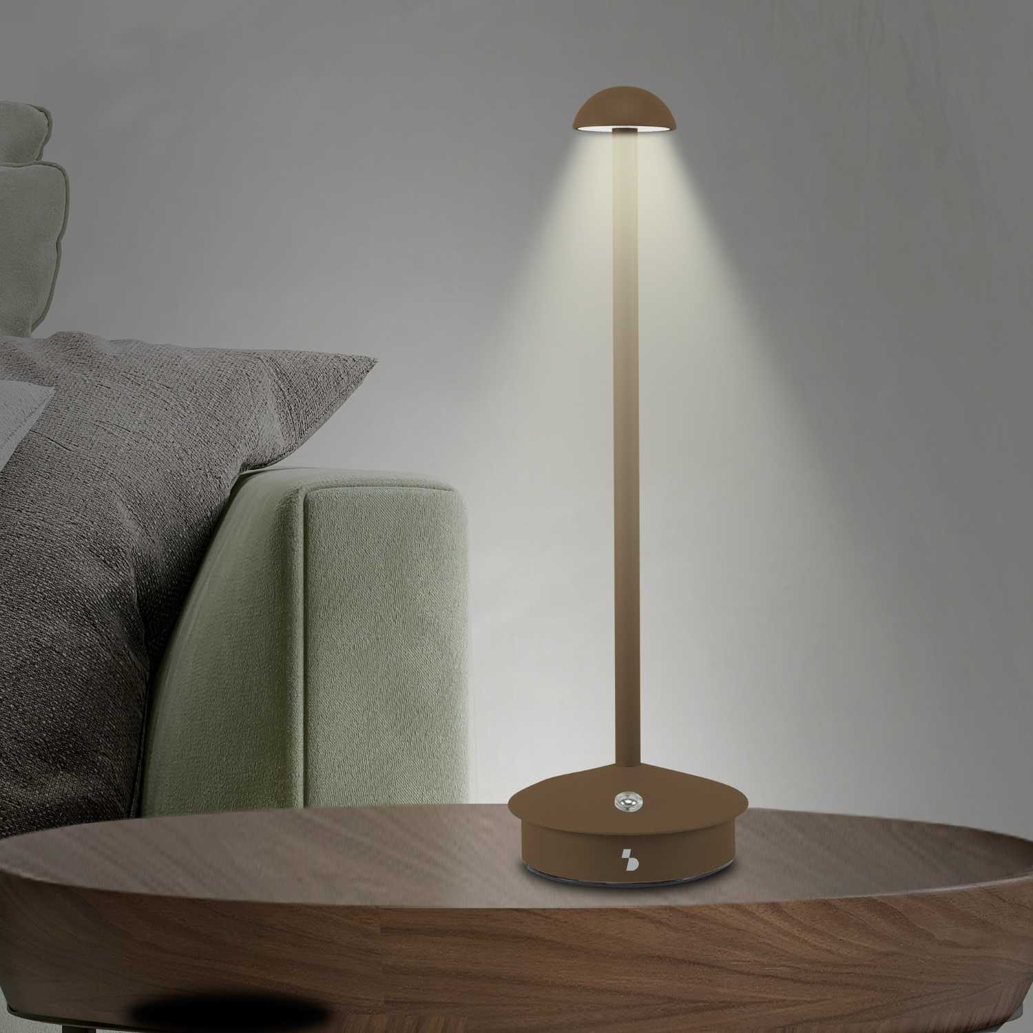 Una lampada marrone con paralume a cupola illumina un tavolo di legno.