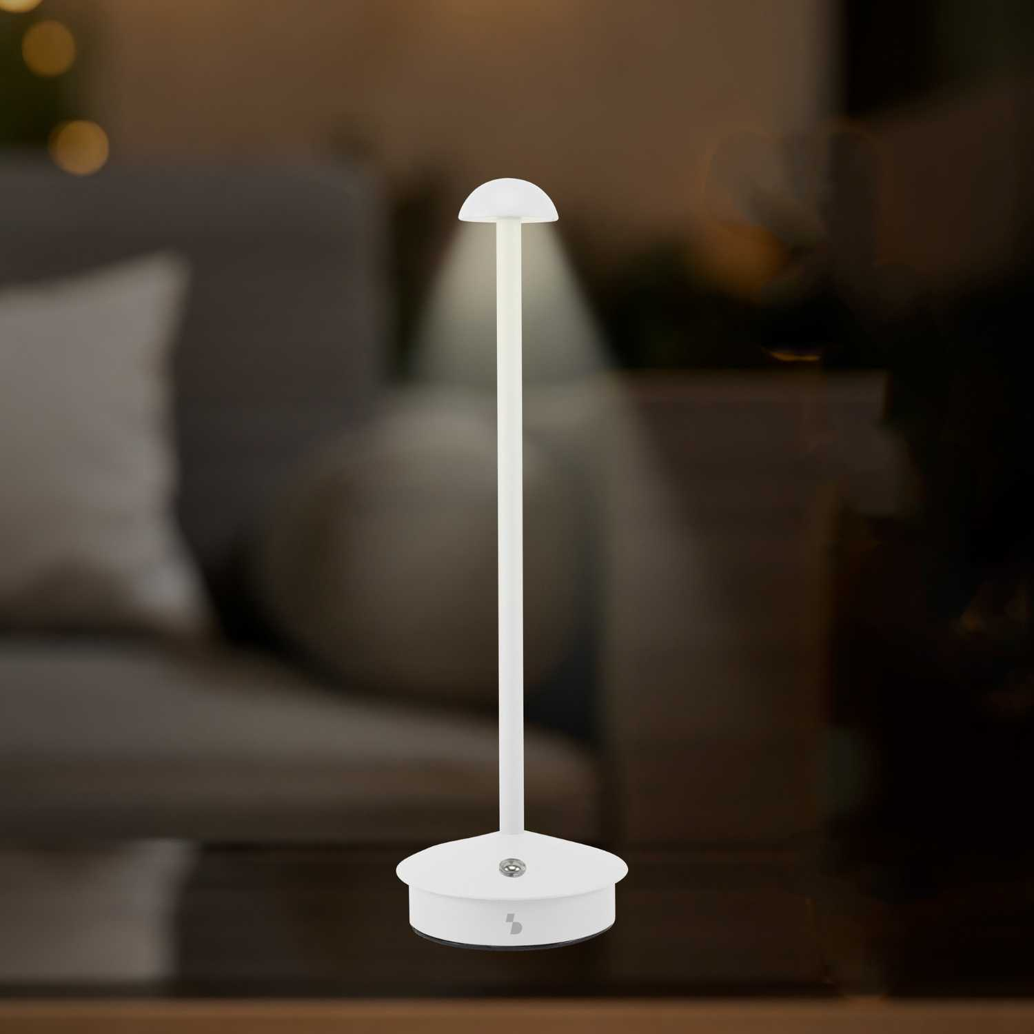 Una lampada da comodino bianca con base rotonda e testa a fungo è accesa su un tavolo.