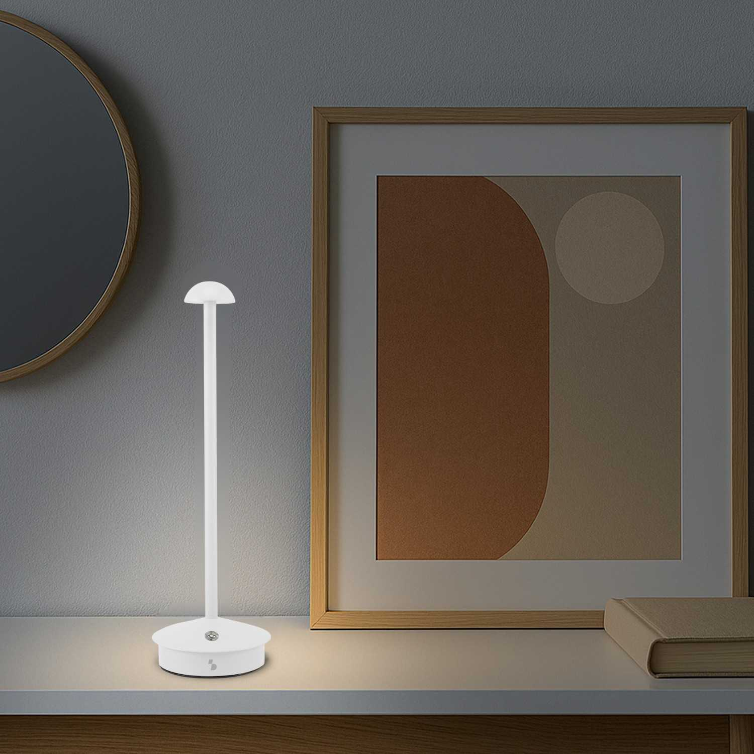 Una lampada da scrivania minimalista bianca si trova su uno scaffale accanto a un'opera d'arte astratta incorniciata.