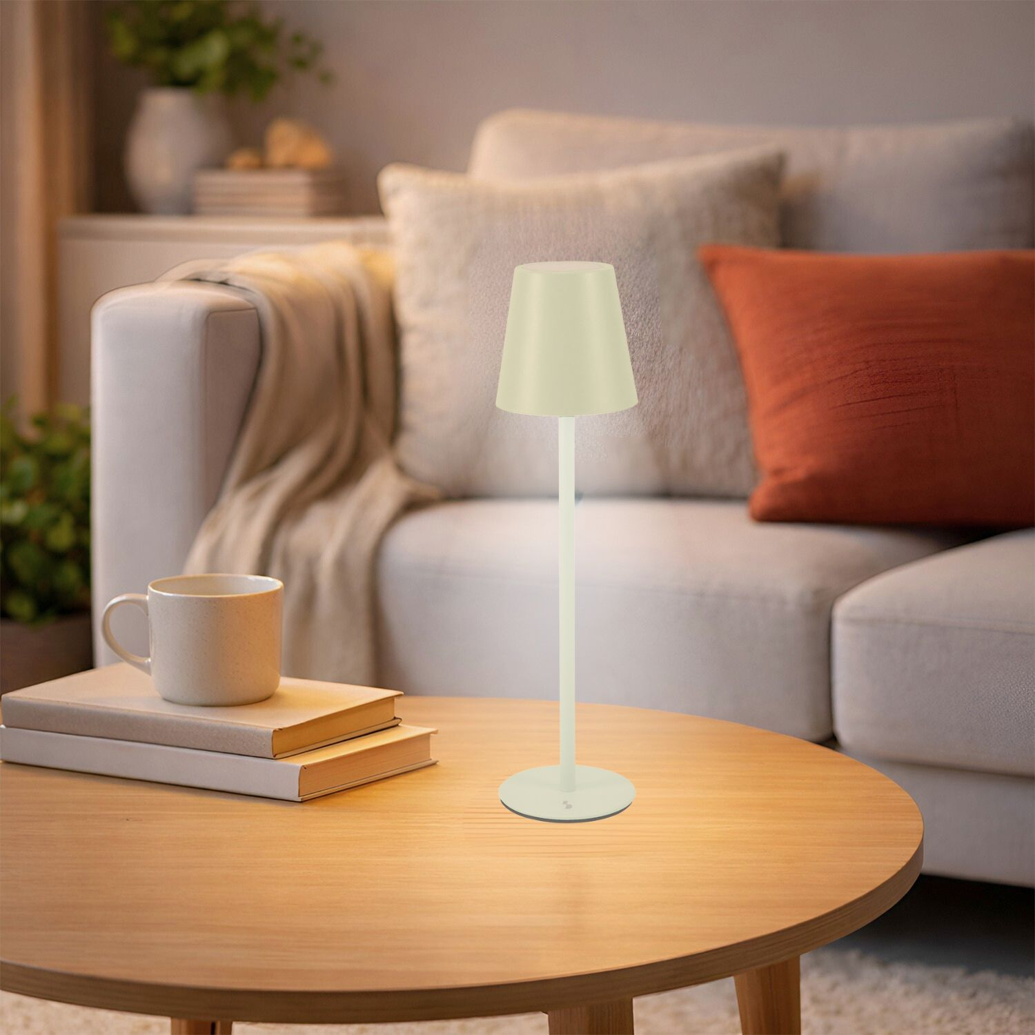 Una piccola lampada si trova su un tavolo di legno accanto a libri e una tazza.