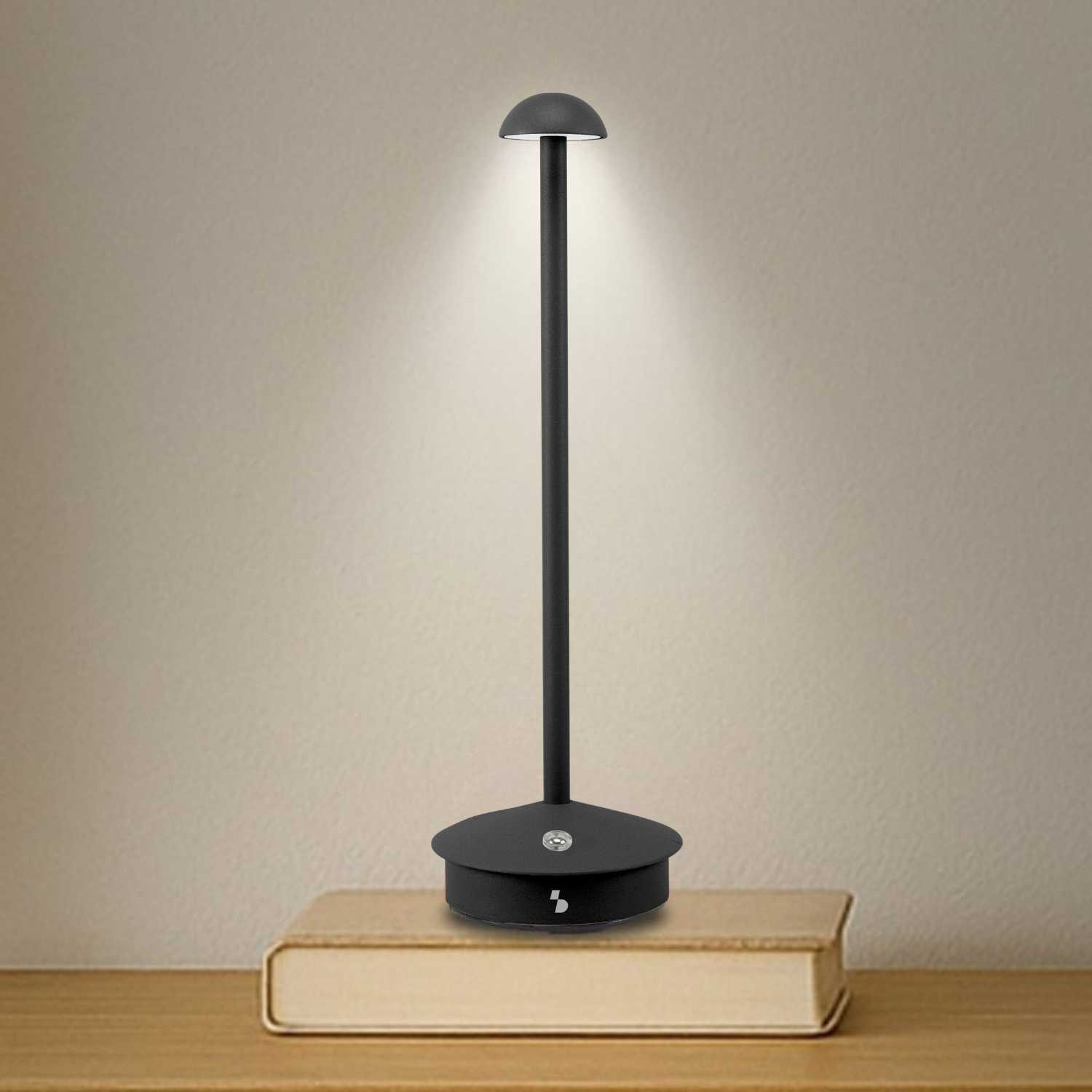 Una lampada da scrivania nera con paralume rotondo si trova su un libro.