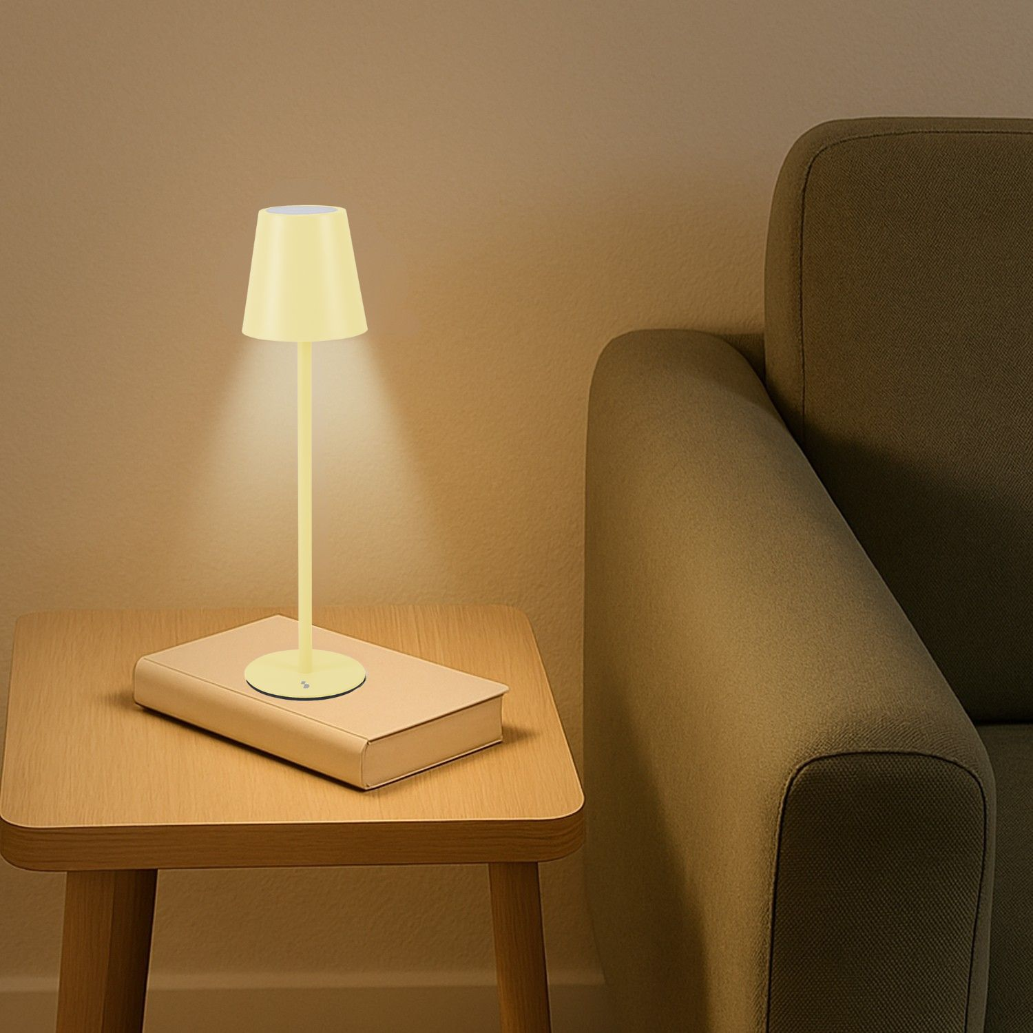 Una lampada gialla è appoggiata su un libro, sopra un tavolo di legno, accanto a un divano.