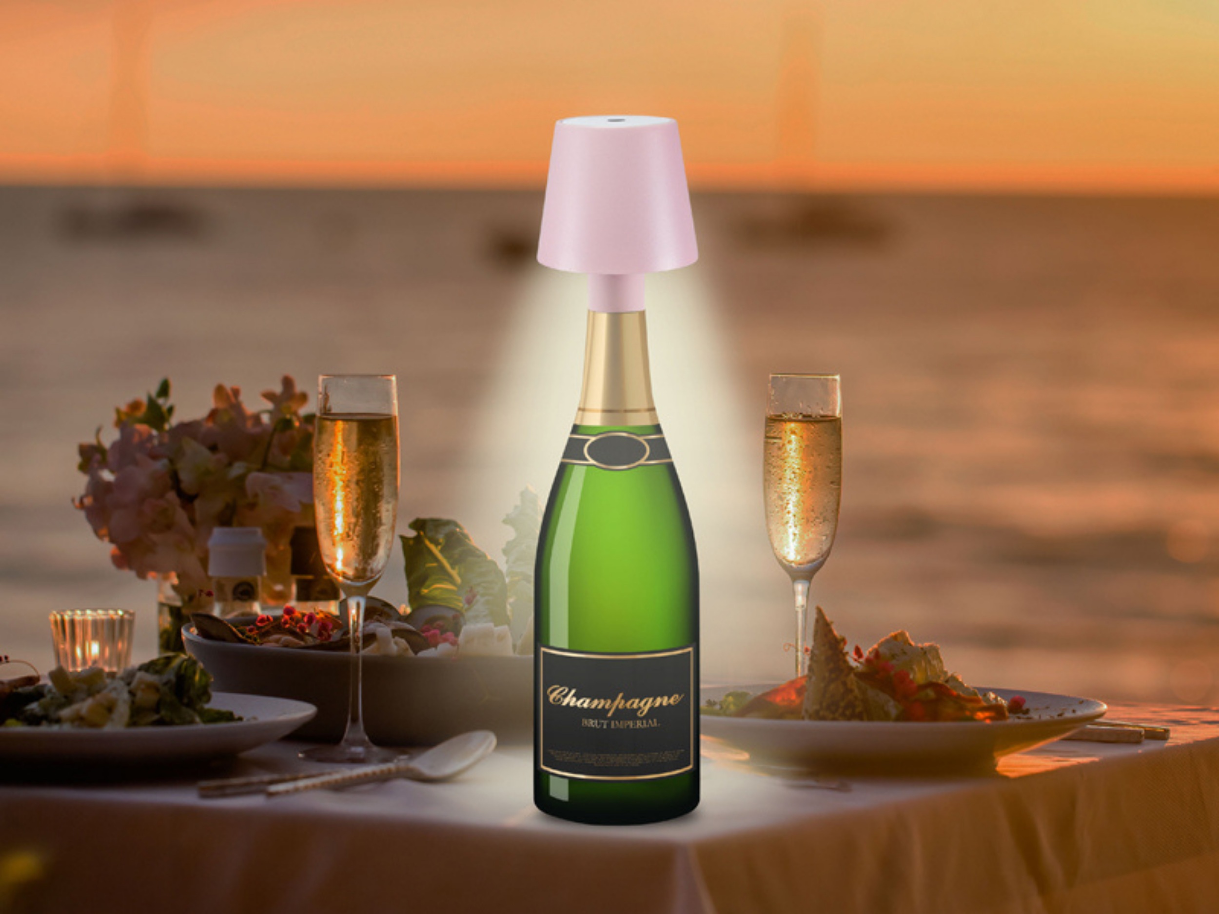 Bottiglia di champagne con lampada rosa al tramonto sul mare, tavola apparecchiata.