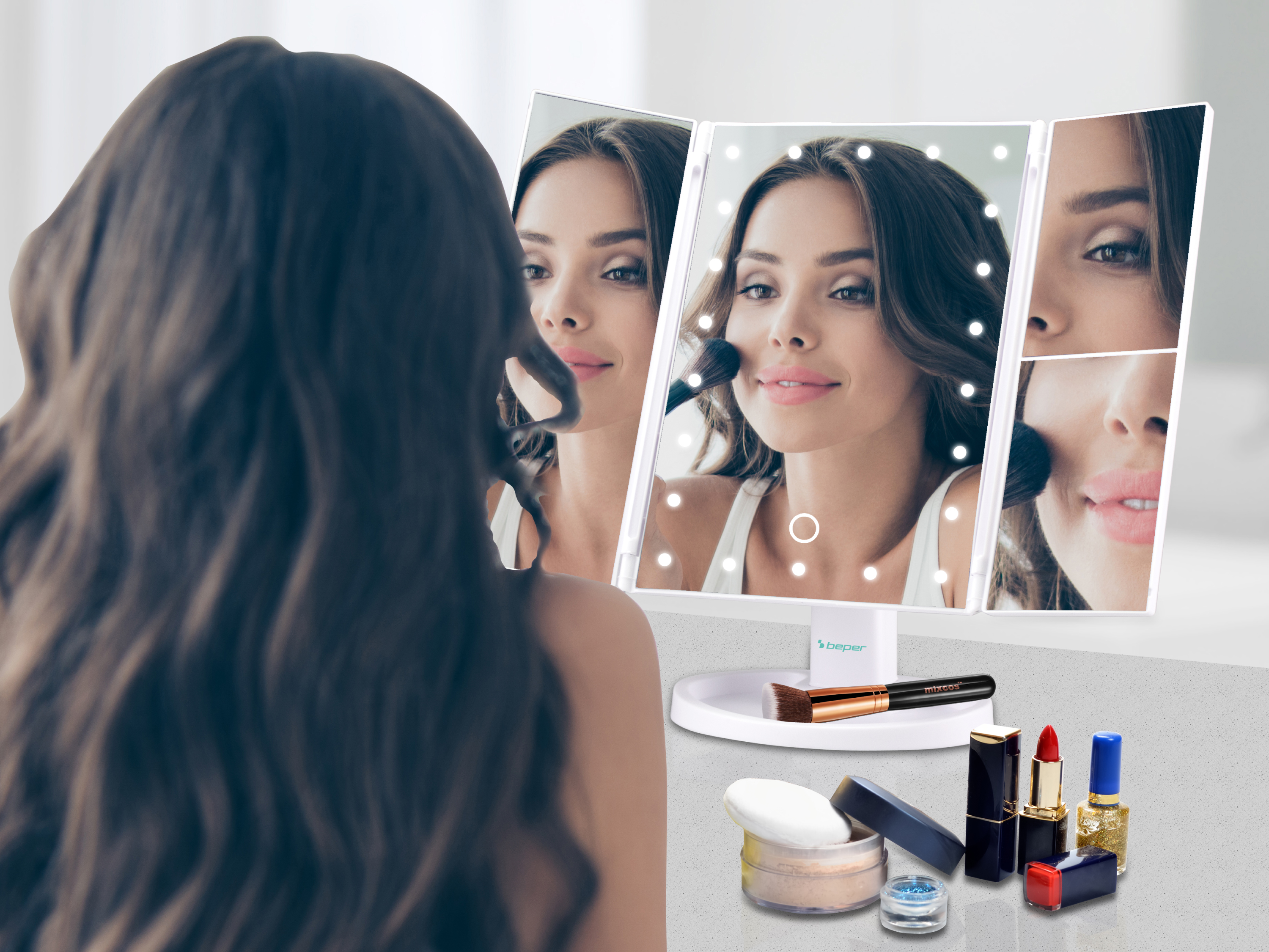 Una donna con i capelli lunghi si trucca davanti a uno specchio illuminato con cosmetici.