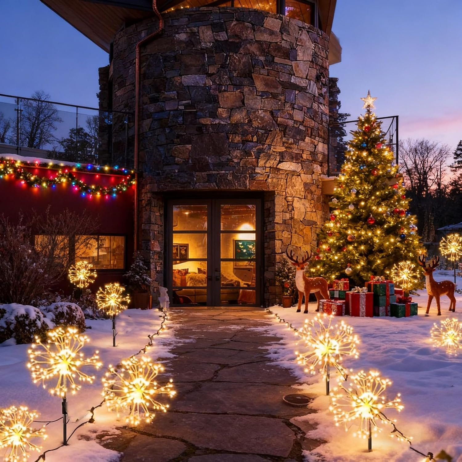 Weihnachtsbaum mit Lichtern, Geschenken und Rentieren im Schnee vor einem Steinhaus.