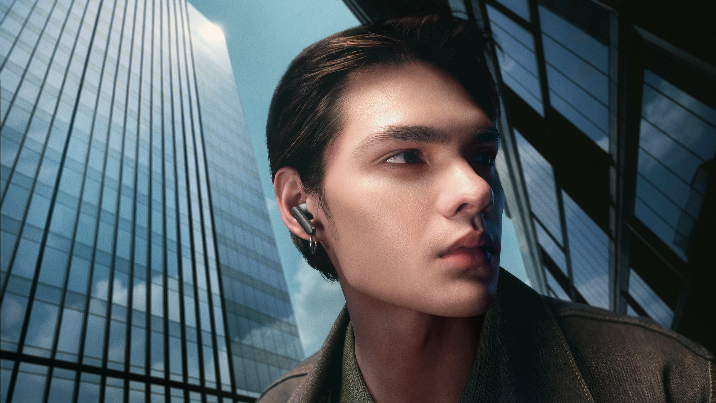 Mężczyzna ze słuchawką w uchu przed szklanymi budynkami