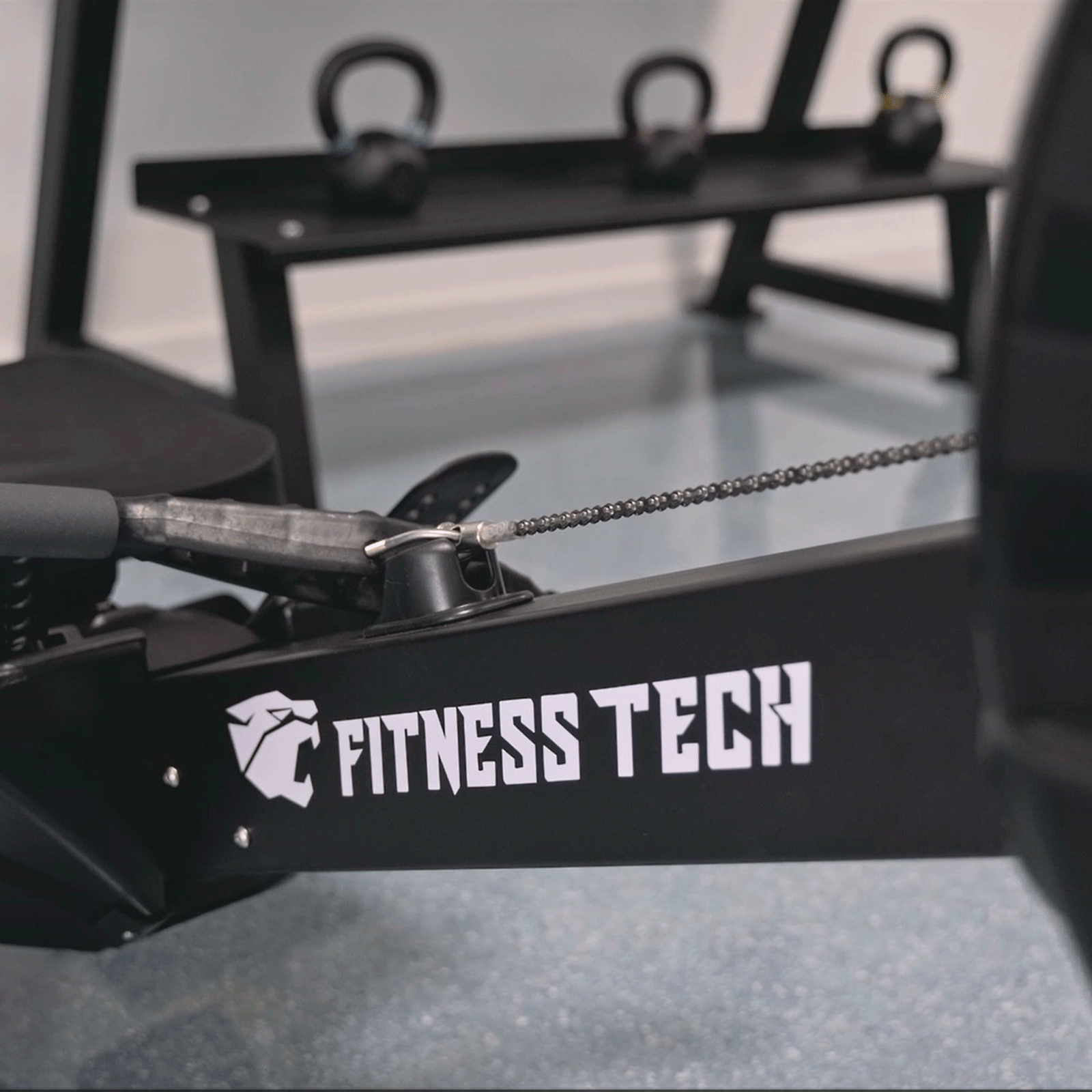Vogatore con catena e kettlebell sullo sfondo.