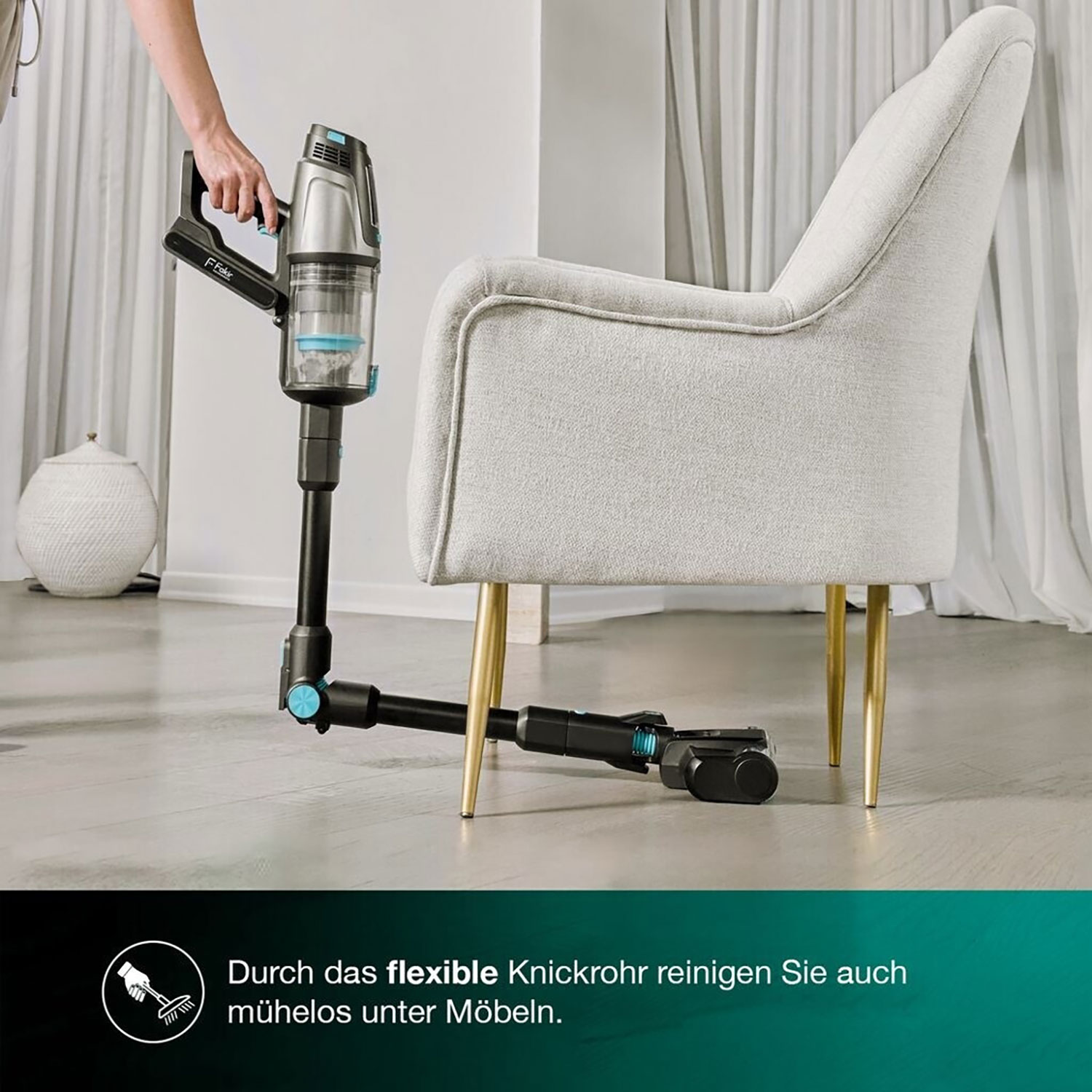 Ein Handstaubsauger mit flexiblem Rohr reinigt unter einem Stuhl.