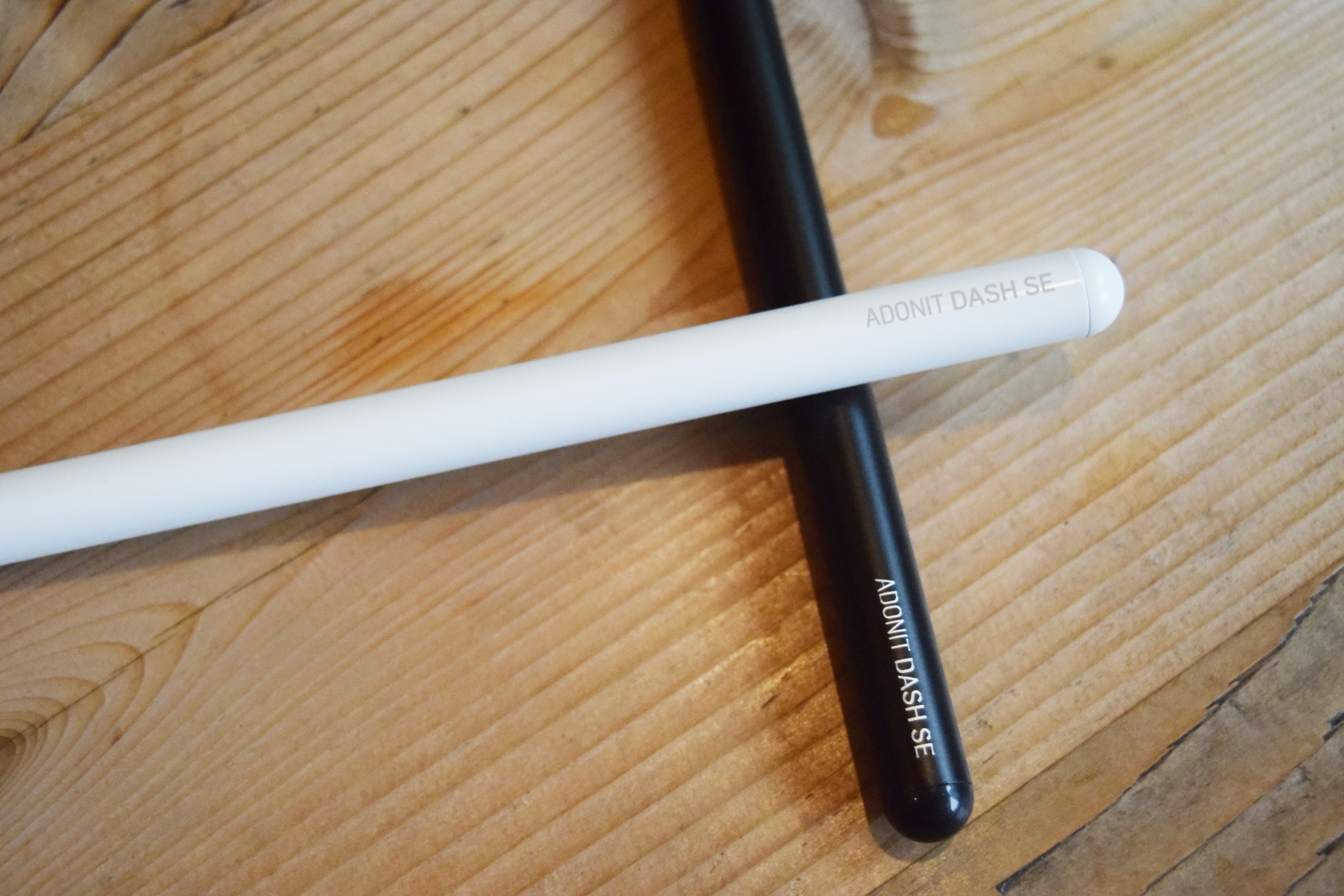Una penna bianca e una nera incrociate su legno.