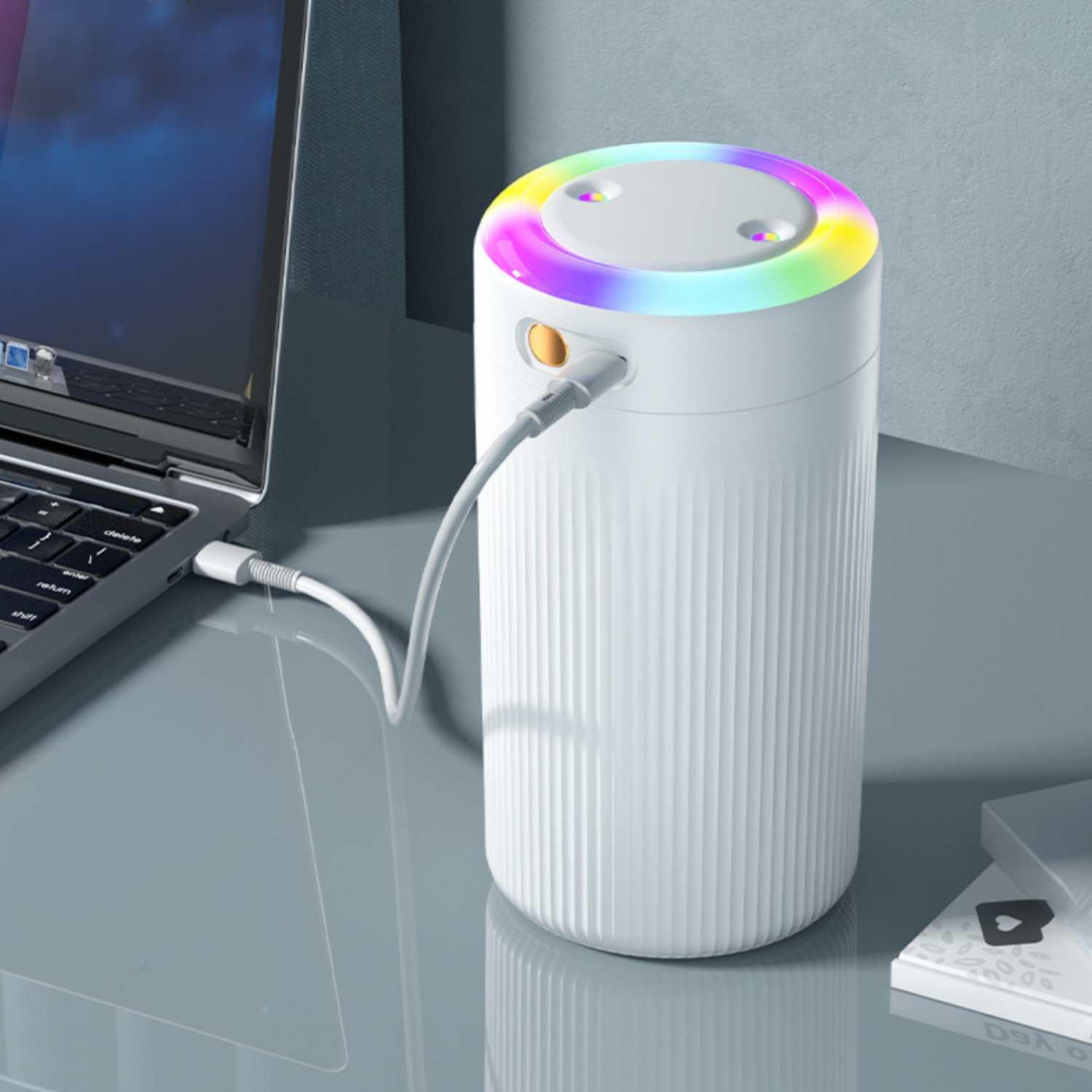 Ein weißer Luftbefeuchter mit buntem LED-Lichtring ist an einen Laptop angeschlossen.