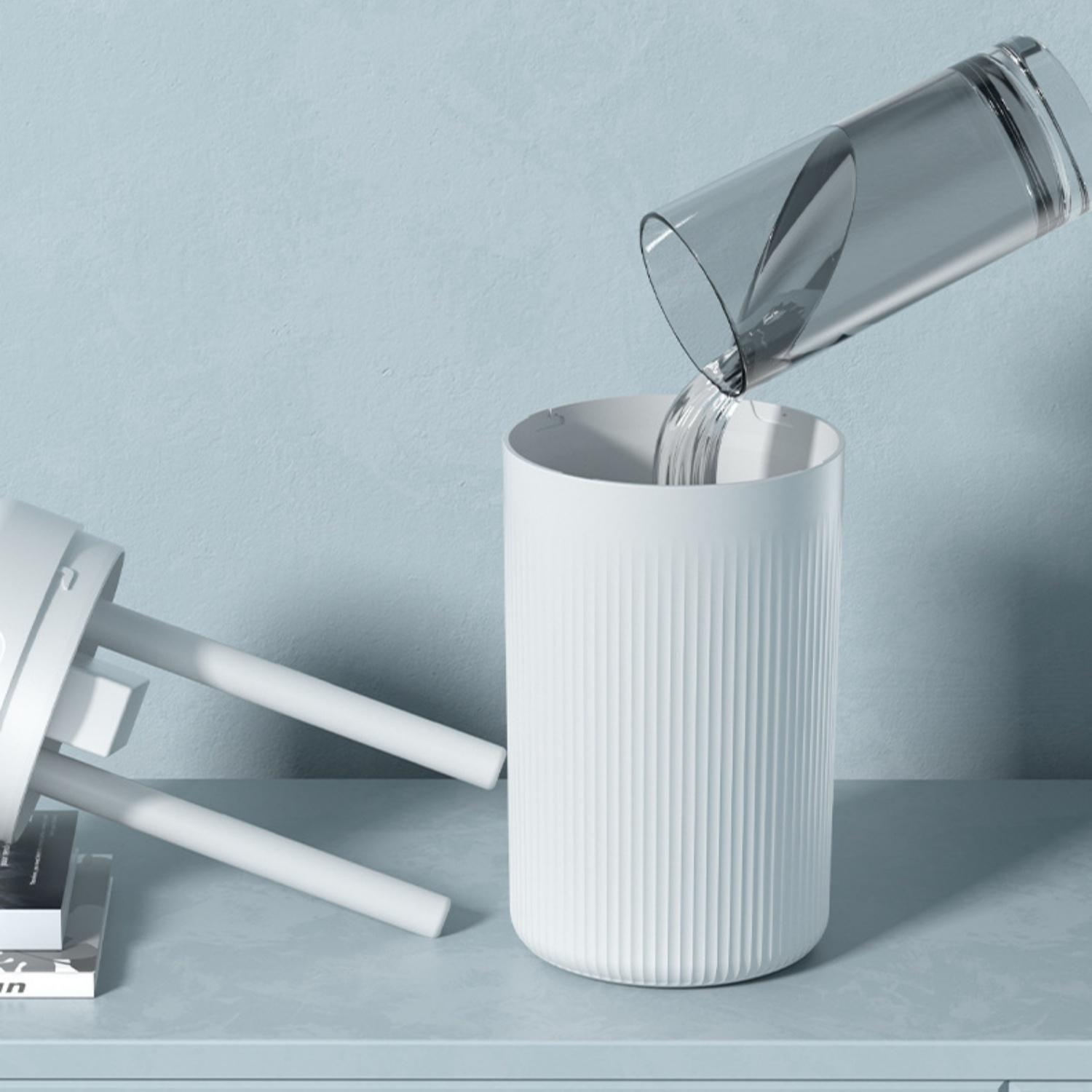 Wasser wird aus einem Glas in einen weißen Becher gegossen.