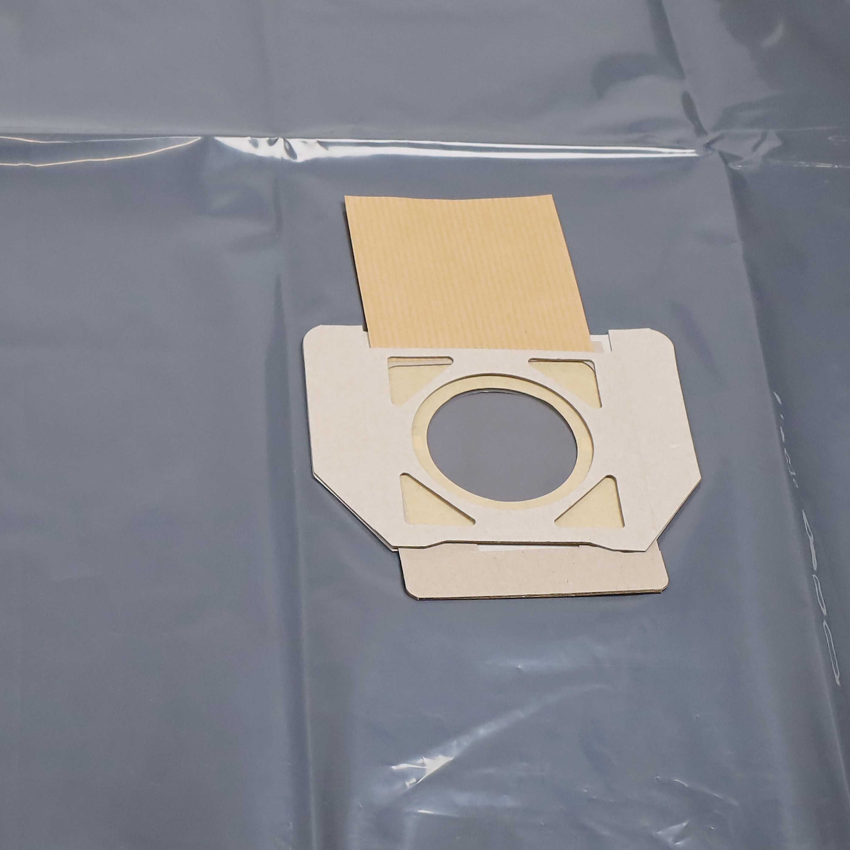 Ein staubbeutel aus Papier mit Kartonrand liegt auf einer grauen Folie.