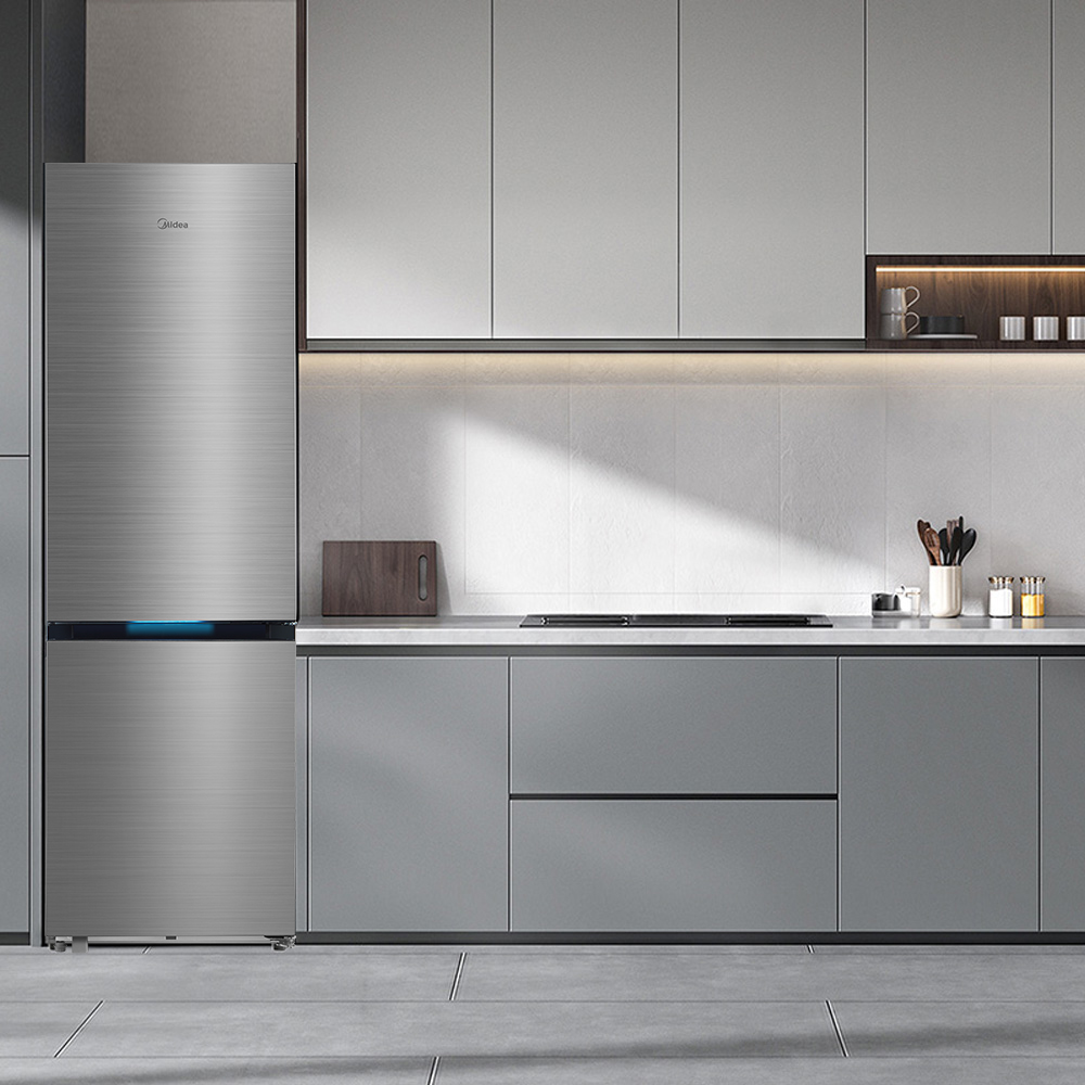 Moderner Edelstahlkühlschrank in einer grauen Küche mit Hängeschränken und Kochfeld.