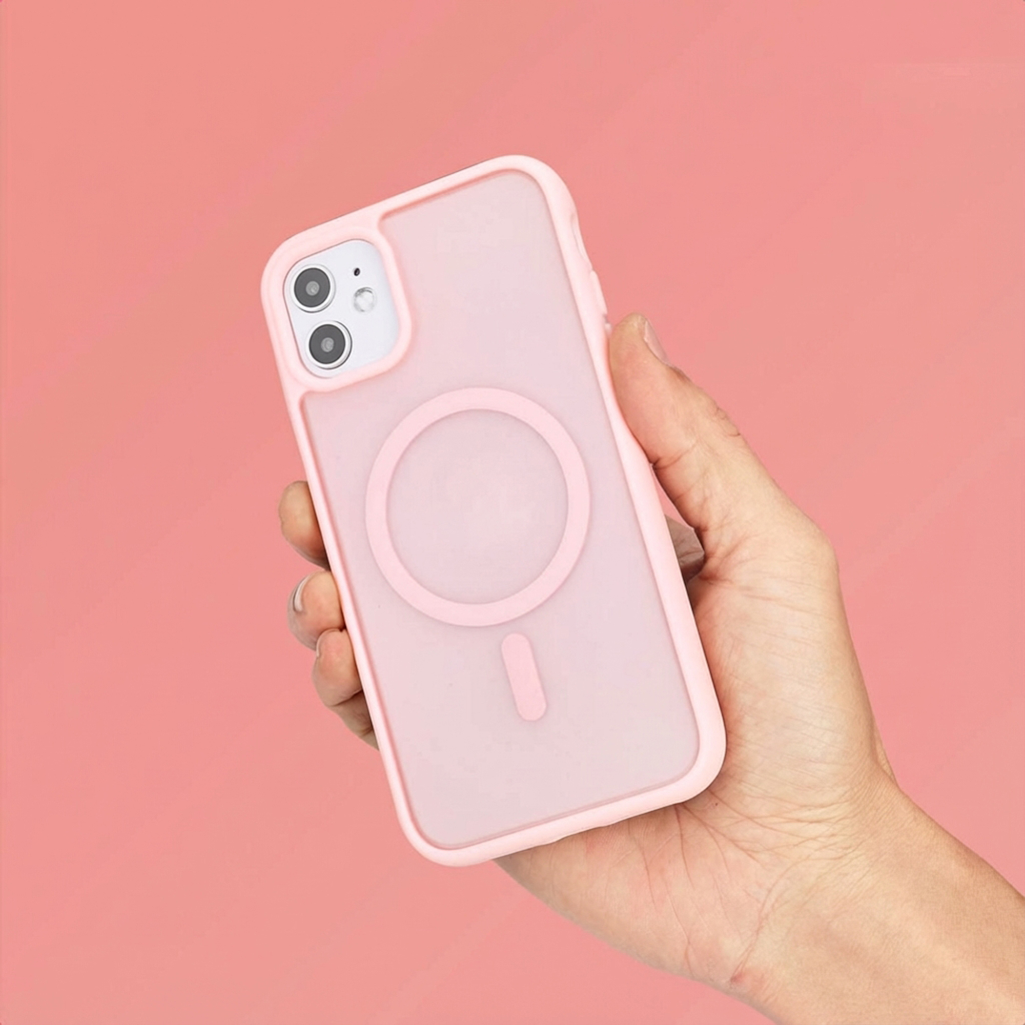 Een hand houdt een lichtroze telefoonhoesje met een magneetring vast.