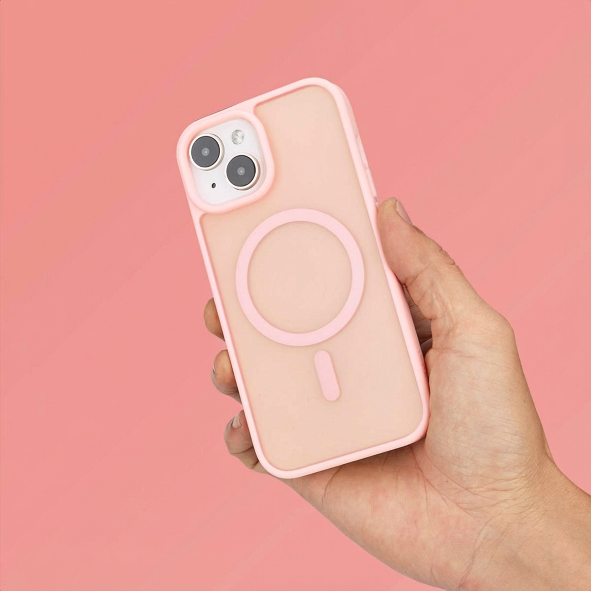 A hand holds a light pink phone case against a coral background. Two cameras are visible.