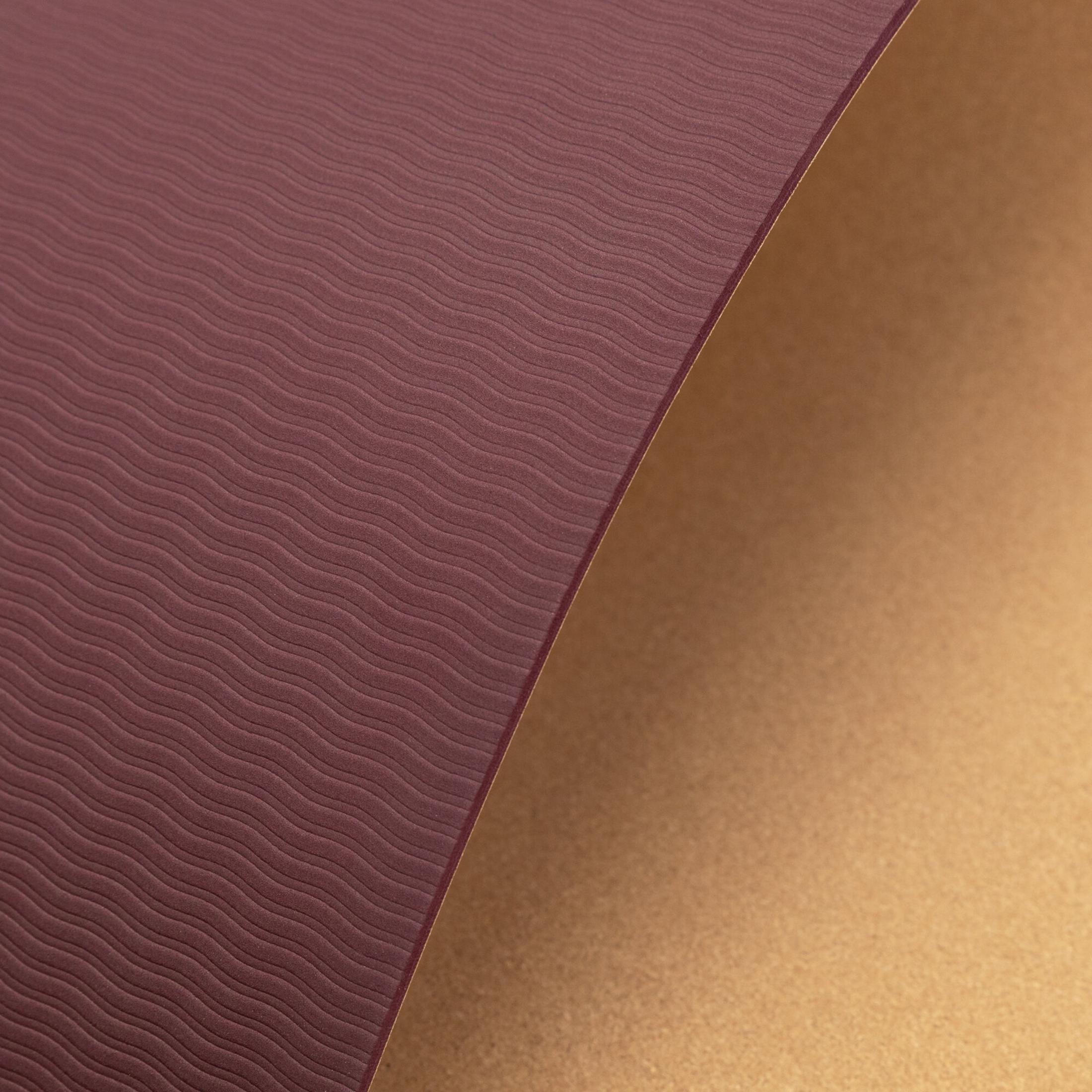 Bordowa mata z falistym wzorem styka się ze złotą powierzchnią.