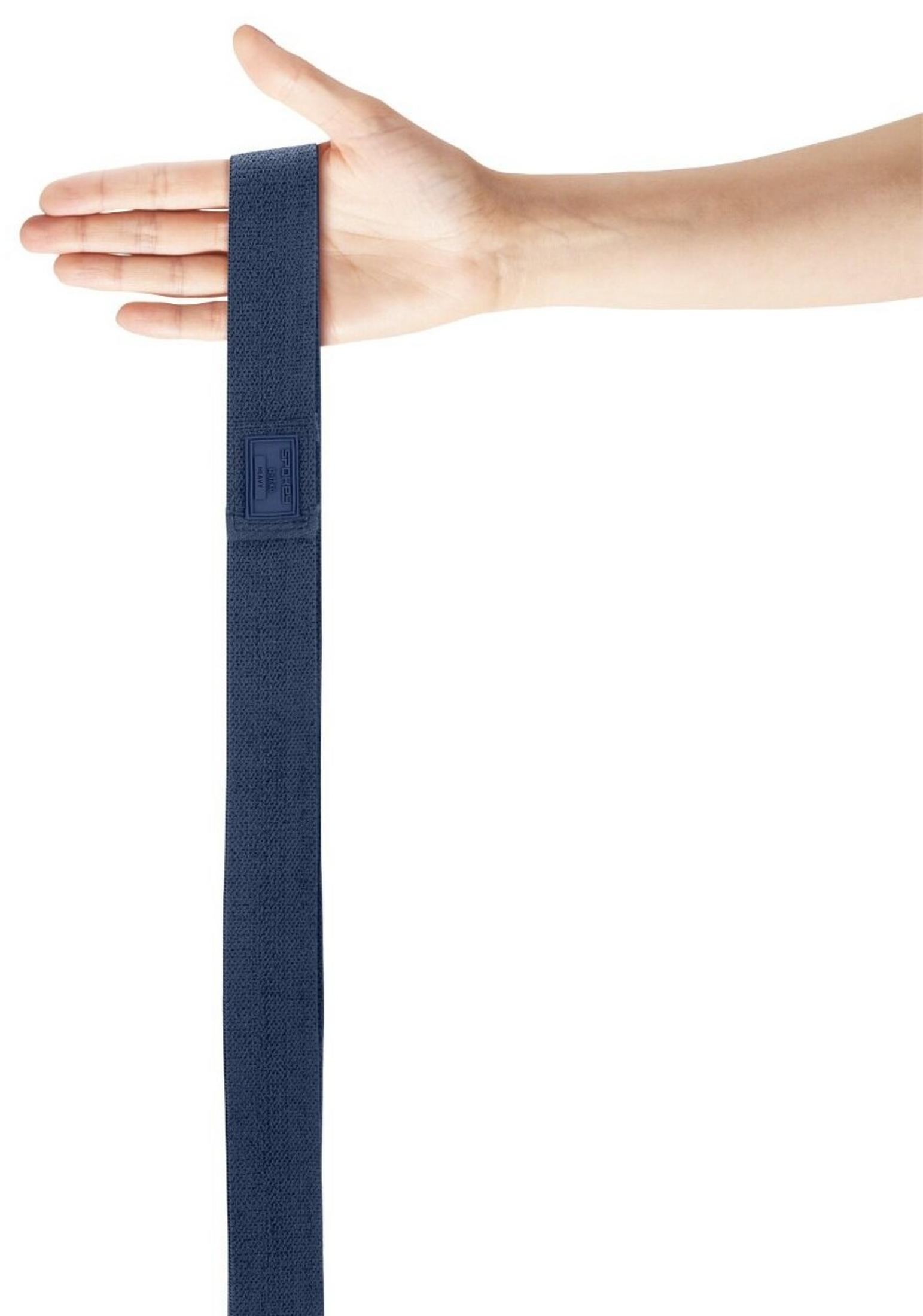 Una mano sostiene una banda elástica azul oscuro con parche de logo.