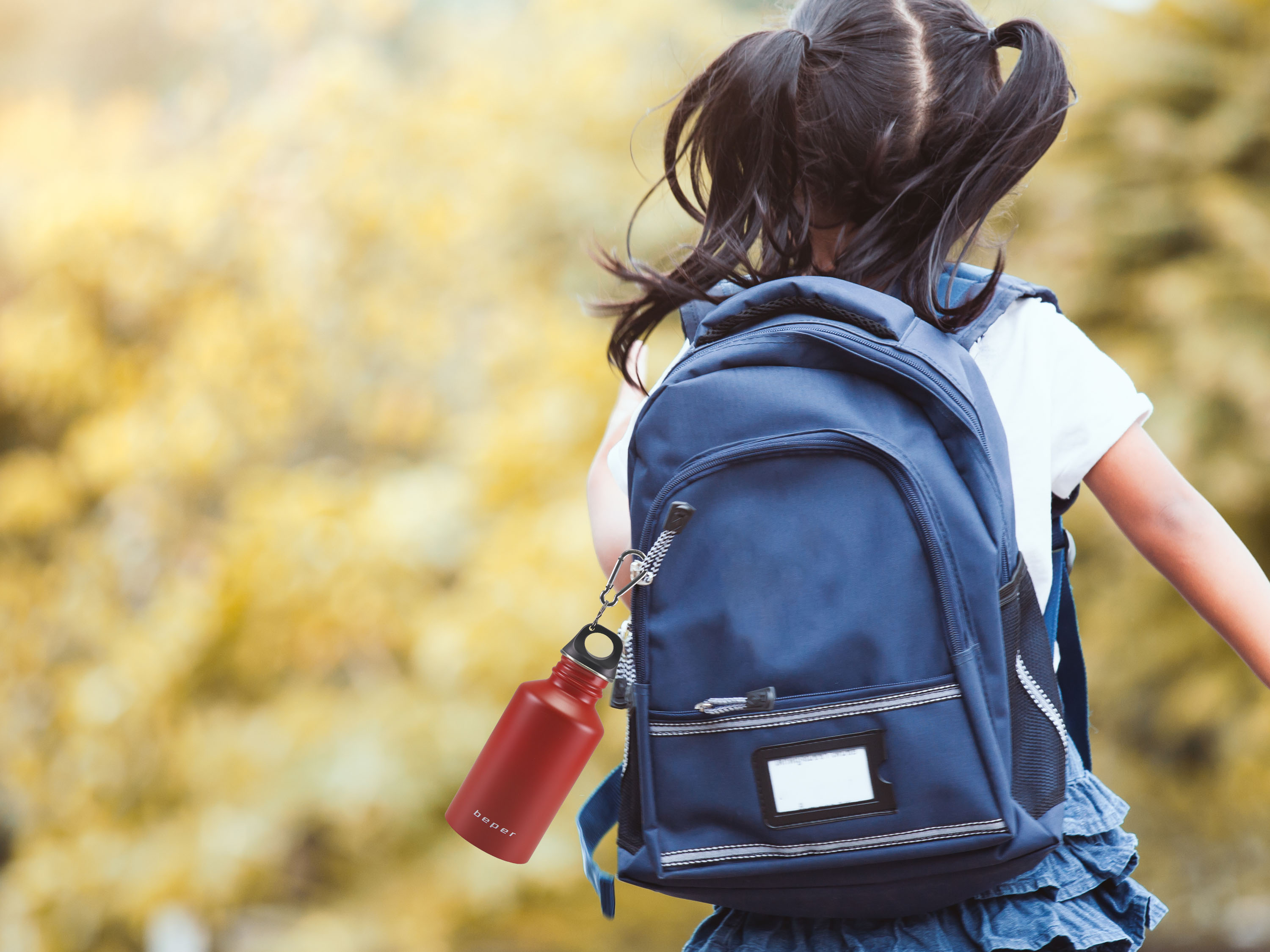 Una bambina con le trecce indossa uno zaino blu e una borraccia rossa.