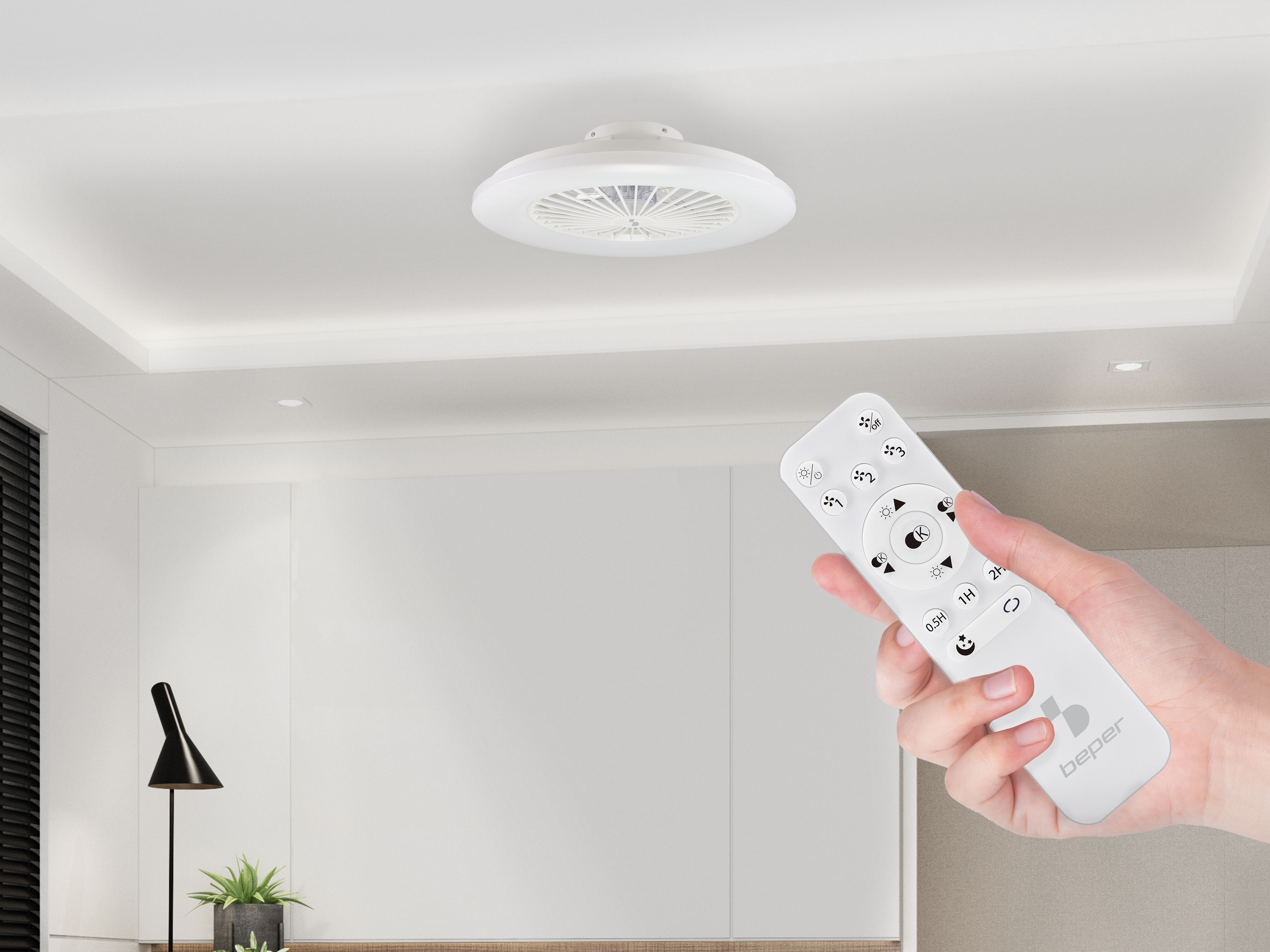 Una plafoniera bianca con ventilatore e una mano con telecomando.