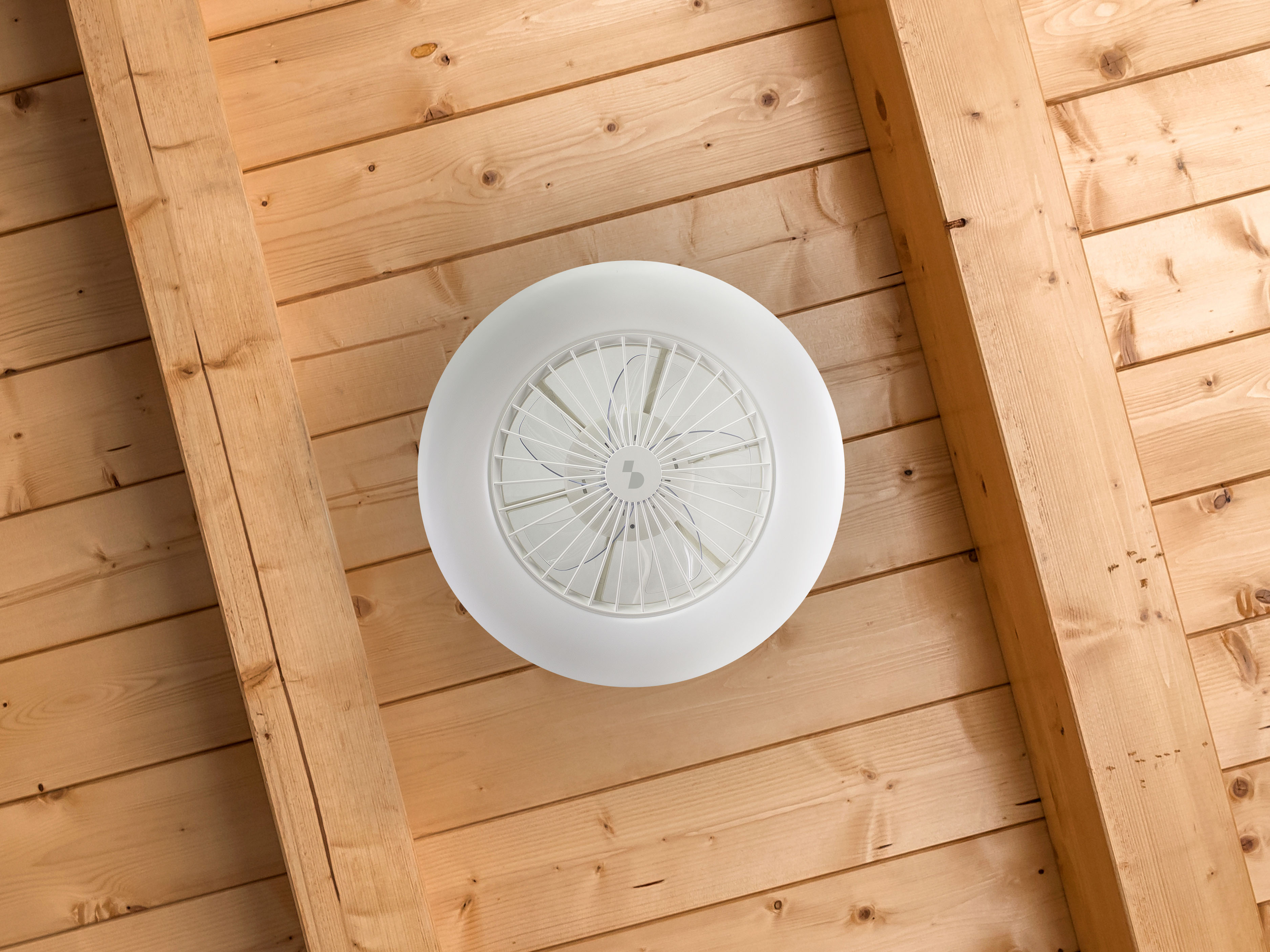 Un ventilatore da soffitto bianco con griglia su un soffitto di legno.