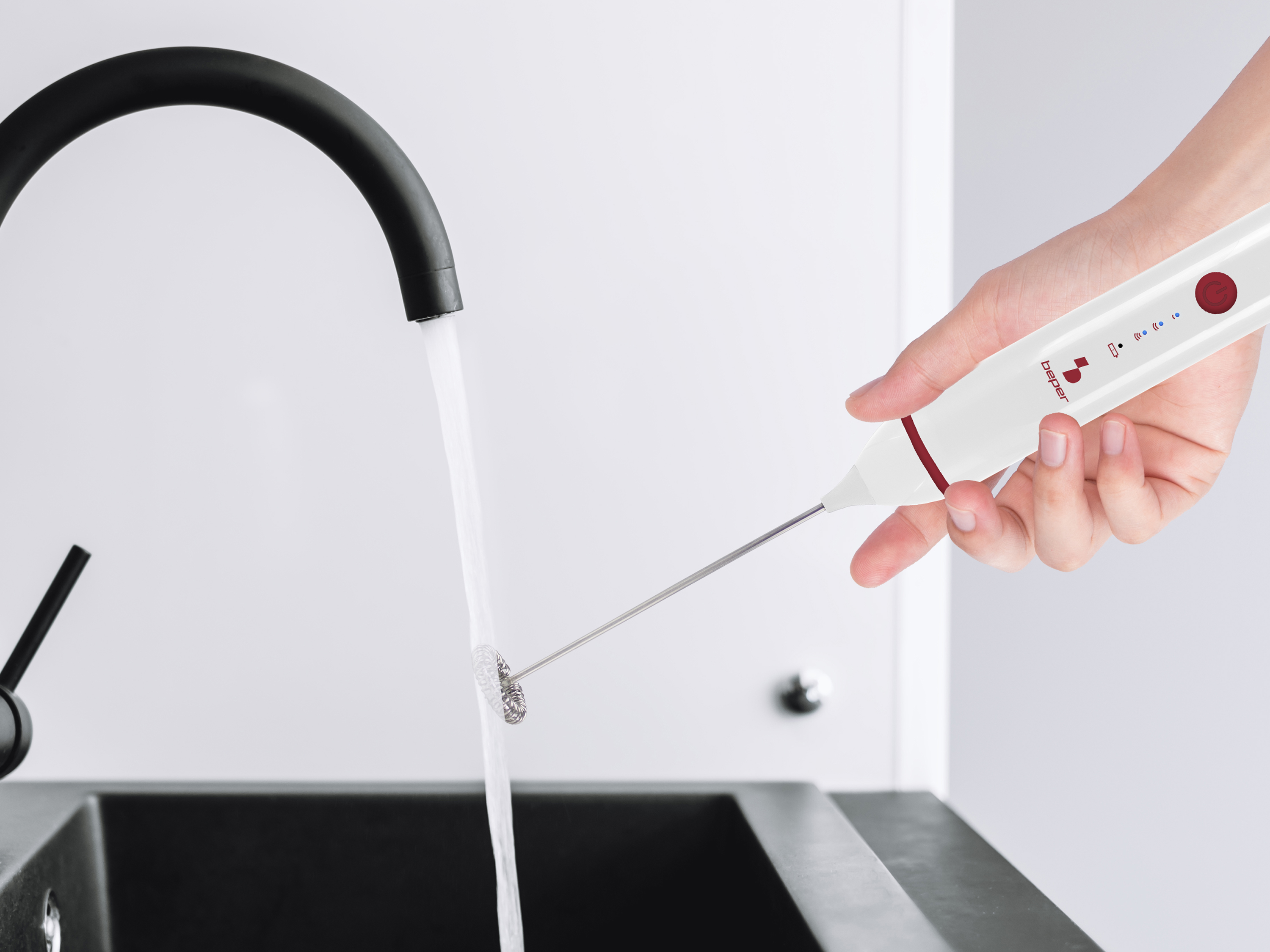 Un montalatte bianco con pulsante rosso sotto acqua corrente.