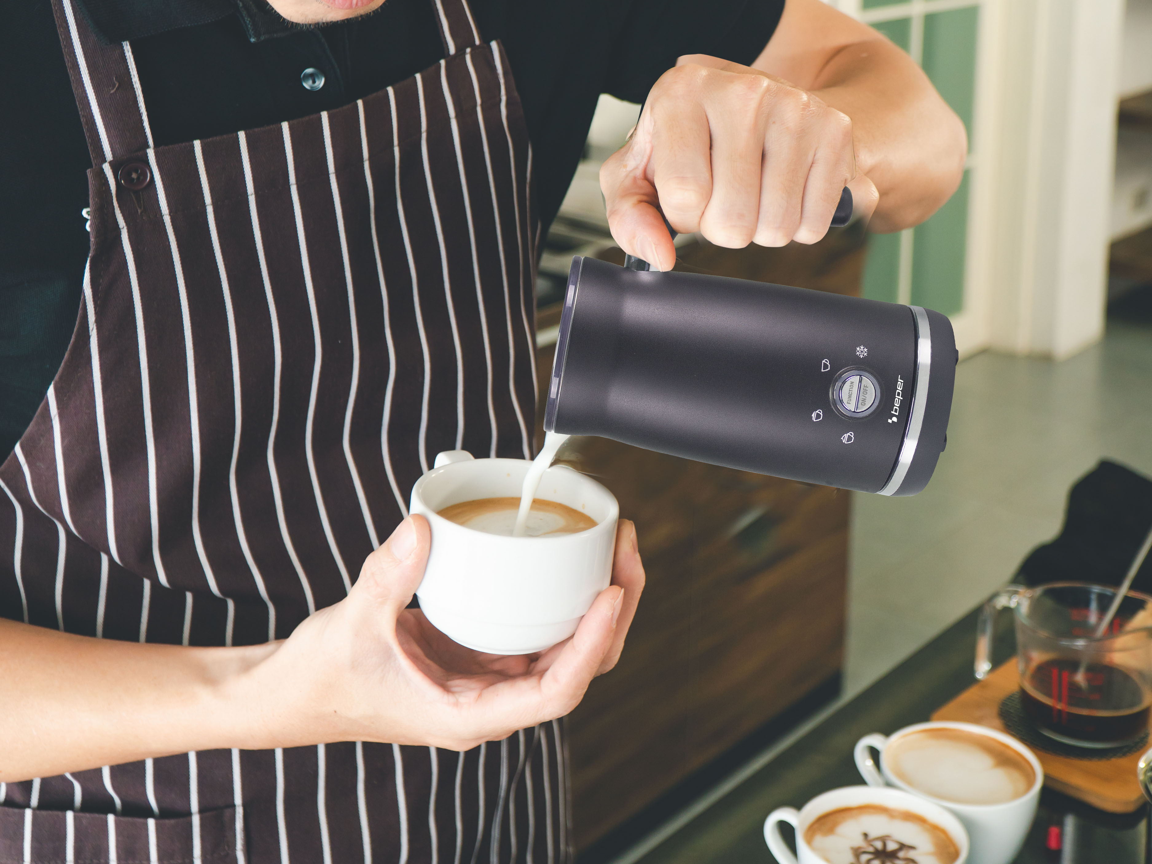 Barista versa latte in una tazza da caffè, indossa un grembiule.