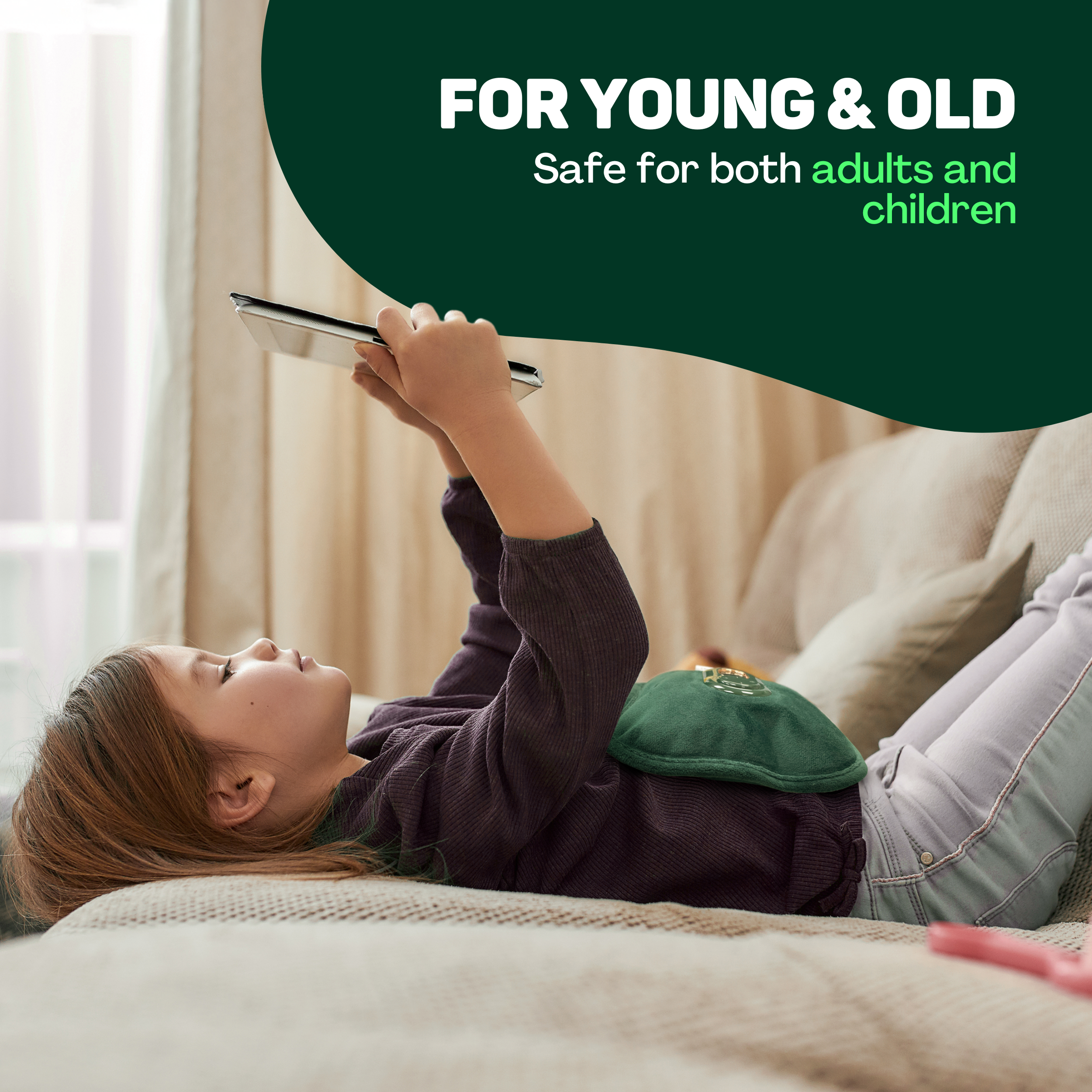 Ein Kind liegt auf einem Sofa und benutzt ein Tablet. Eine grüne Wärmflasche liegt auf seinem Bauch.