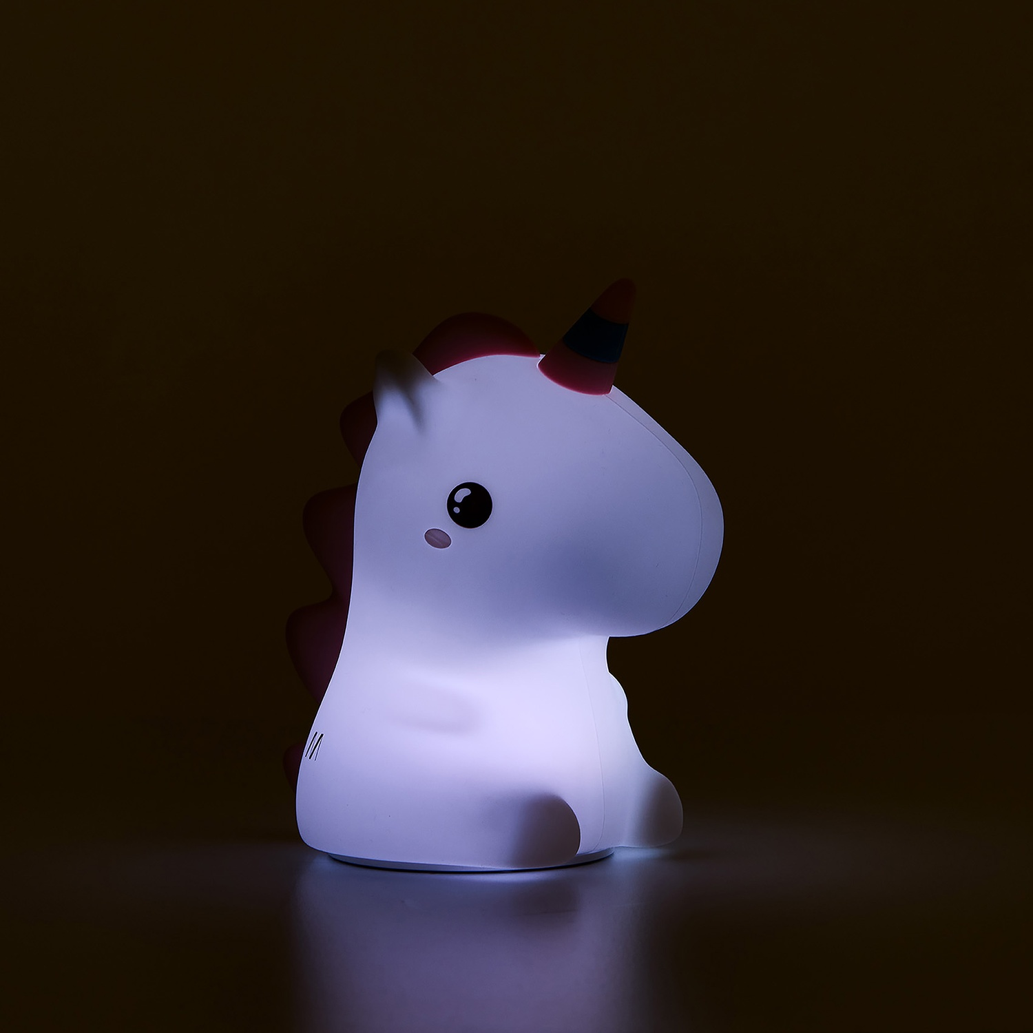 Una lampada unicorno bianca luminosa con accenti rossi siede su una superficie scura.