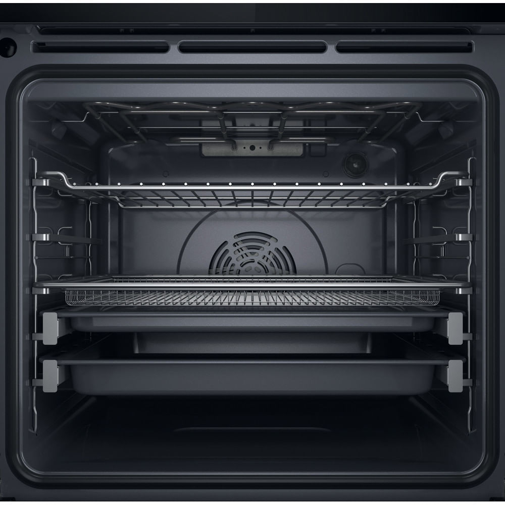 Interno di un forno scuro con tre livelli, griglie e teglie.