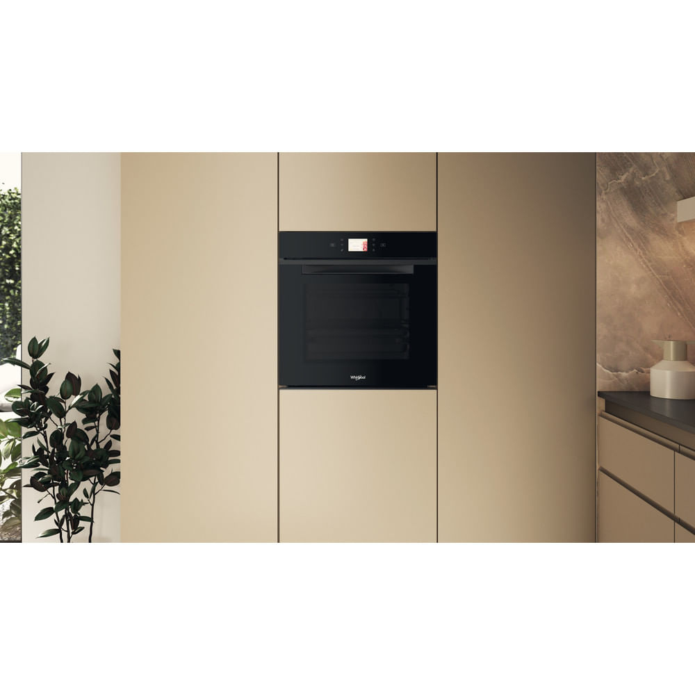 Un forno nero moderno è integrato in eleganti mobili da cucina marrone chiaro.
