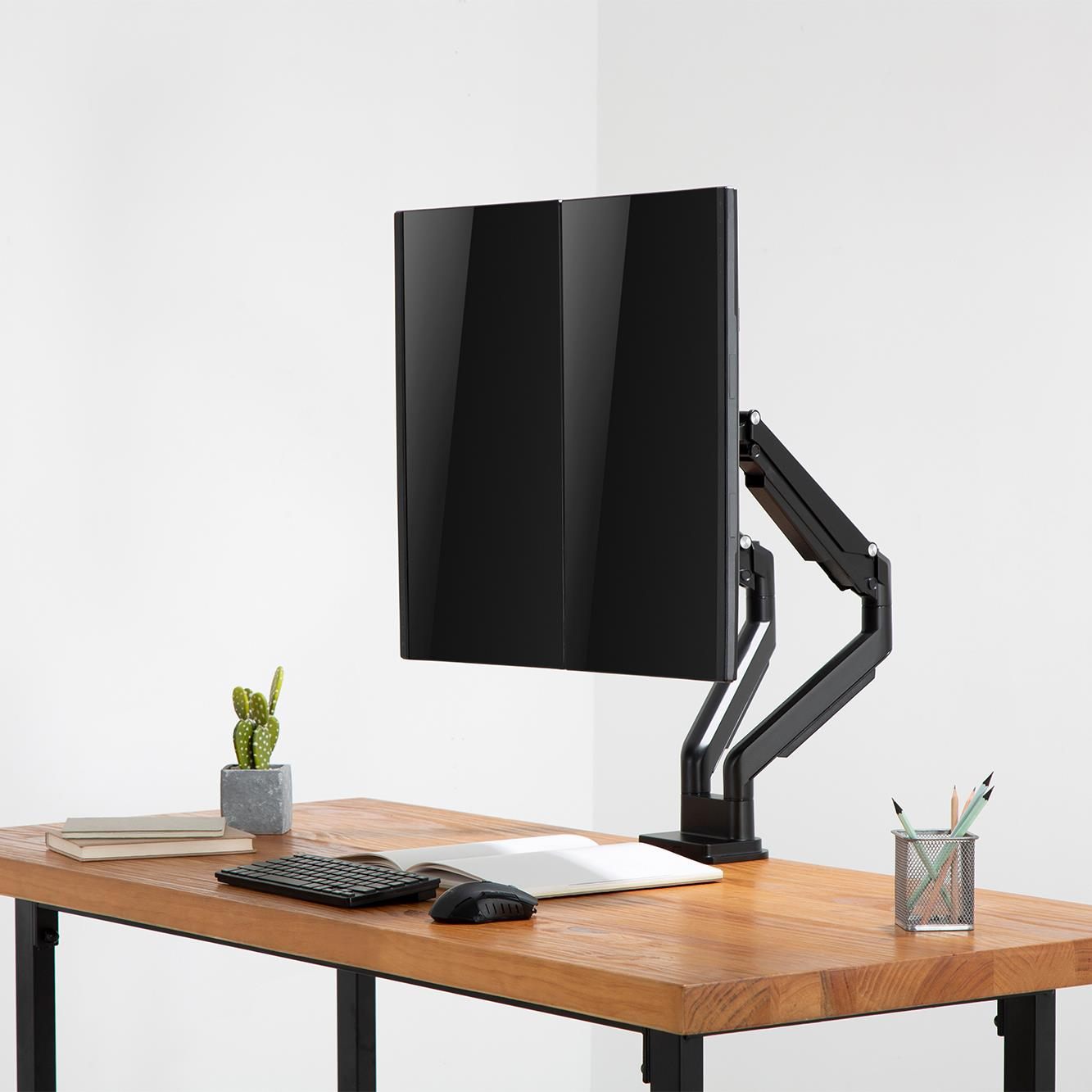 Dwa pionowe monitory na biurku z klawiaturą, myszą i kaktusem.