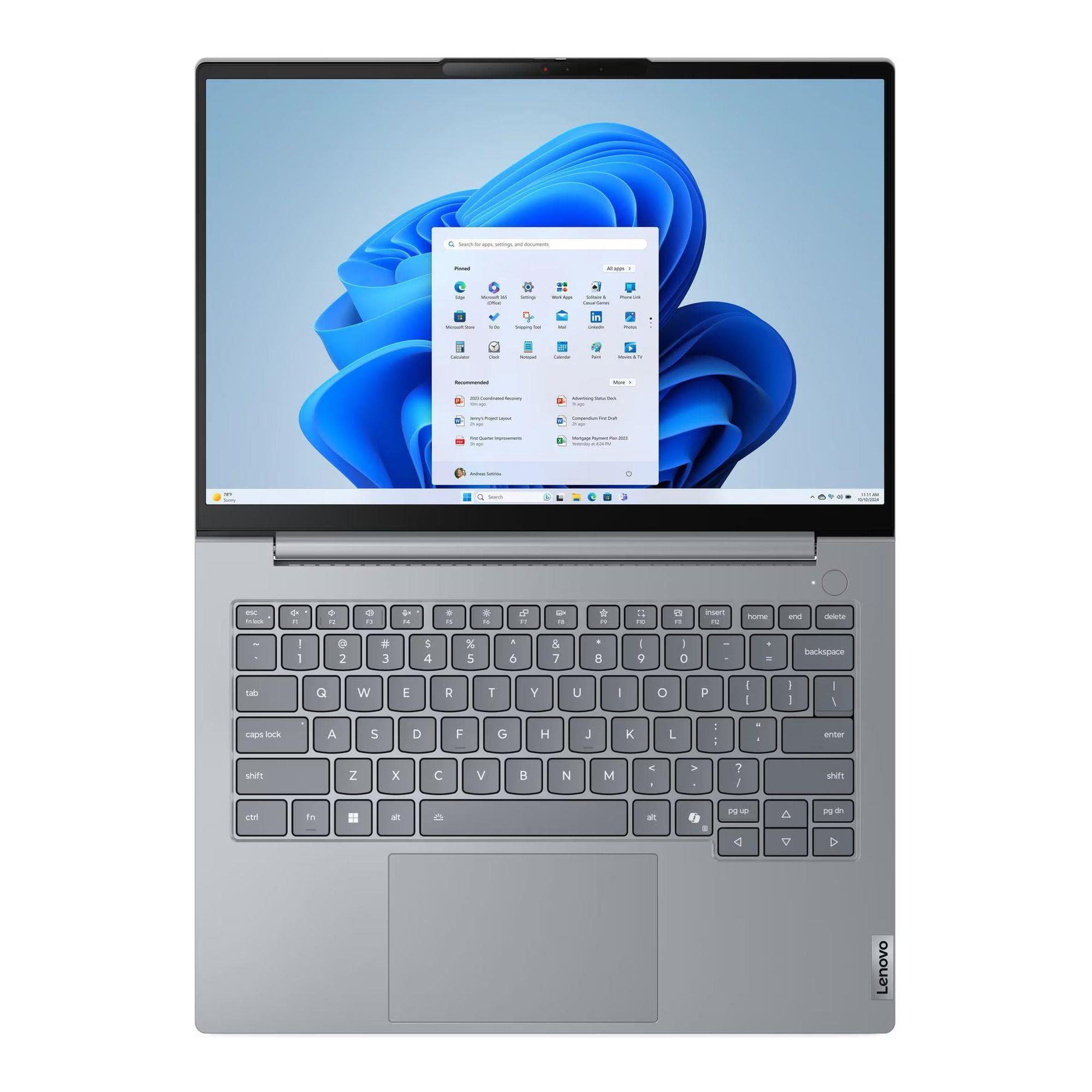 Otwarty laptop z szarą obudową i klawiaturą. Na ekranie widnieje system Windows 11 z aplikacjami.