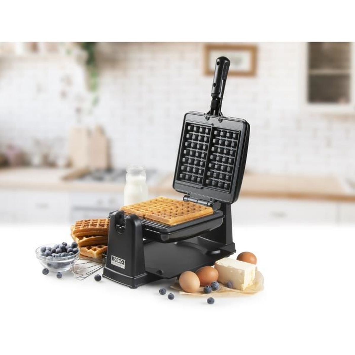 Ein schwarzer Waffelautomat mit fertigen Waffeln, Beeren, Eiern und Butter.