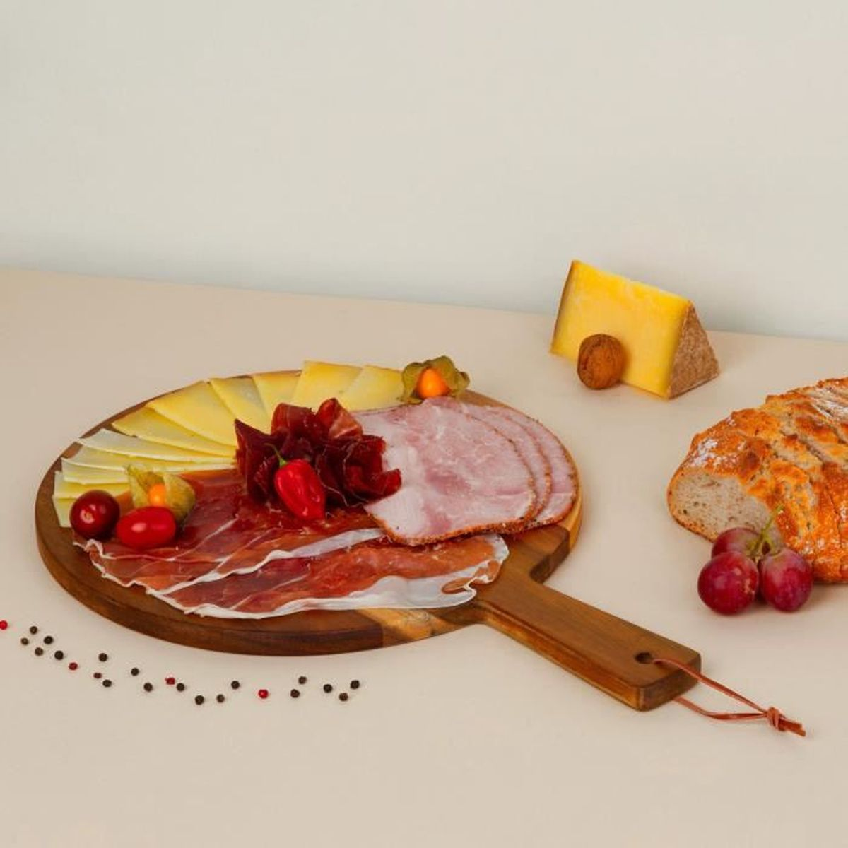 Tagliere di formaggio, prosciutto e salame con pane, uva e pepe.