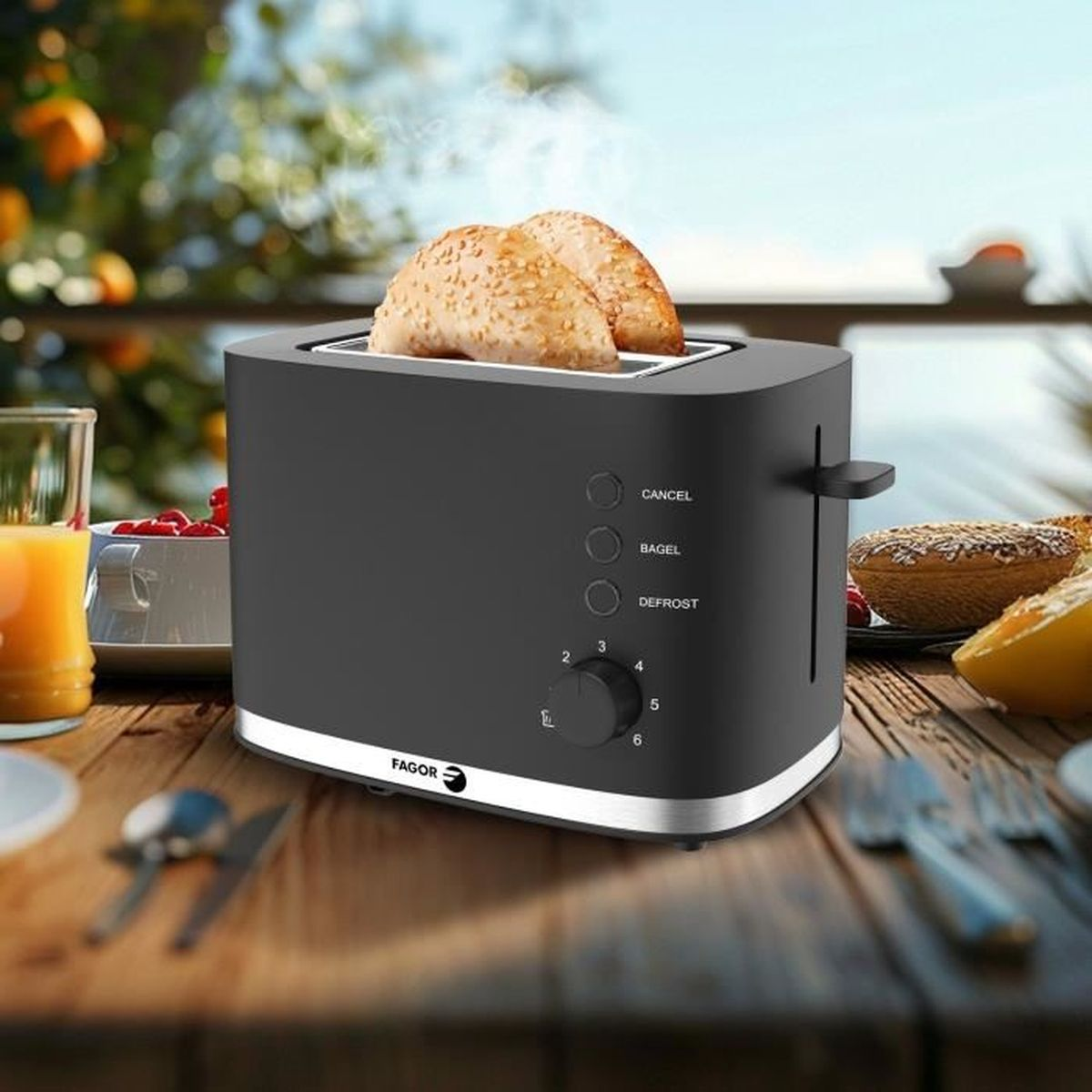 Ein schwarzer Toaster mit zwei Bagels, Dampf steigt auf. Saft und Früchte daneben.