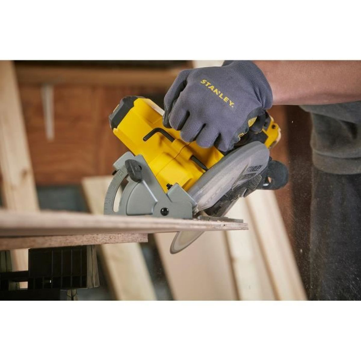 Hand mit Handschuh benutzt Kreissäge, um Holz zu schneiden. Staub fliegt.