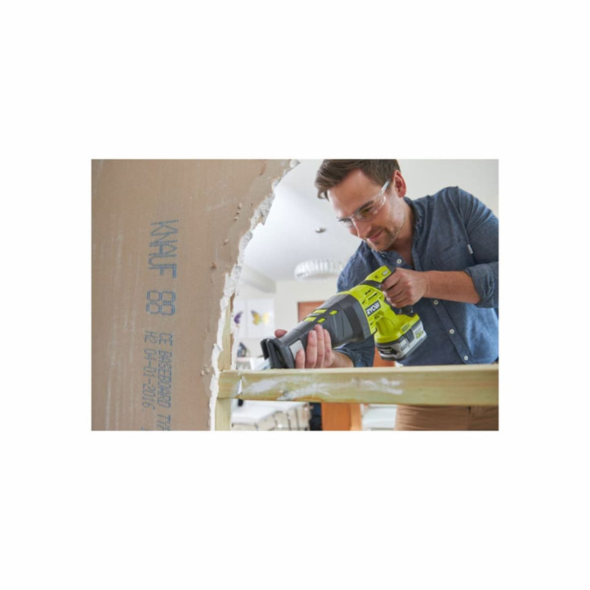 Hombre con gafas de seguridad usa sierra sable en madera.