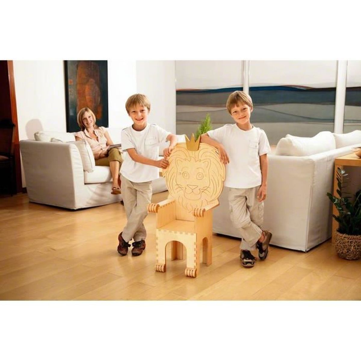 Dwóch chłopców obok drewnianego krzesła z motywem lwa. Kobieta siedzi w tle.