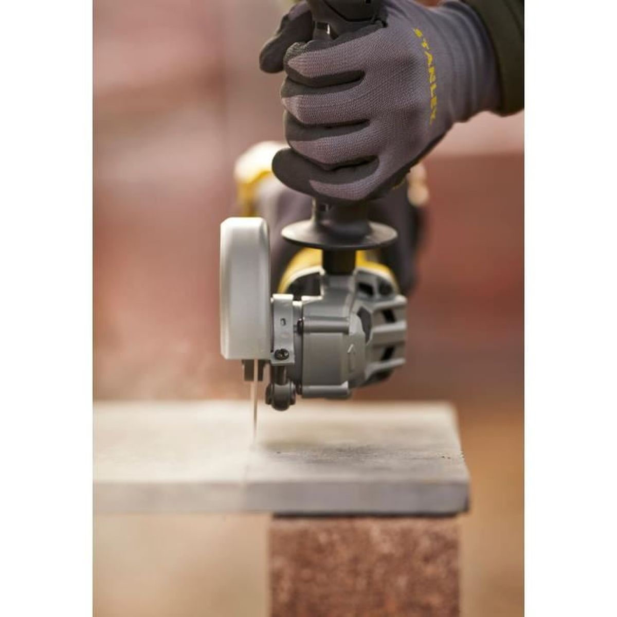 Mano con guante usa amoladora angular para cortar piedra.