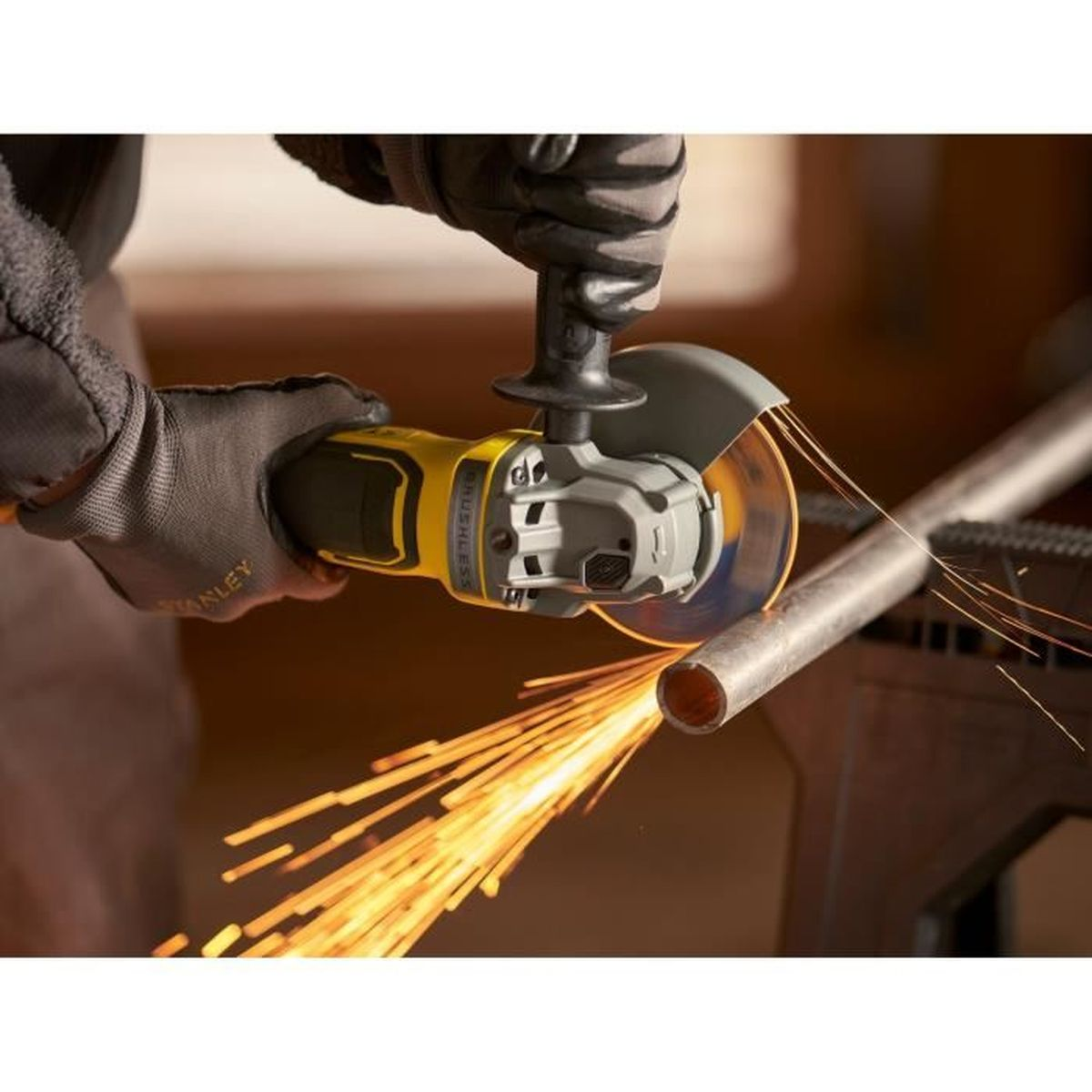 Una mano enguantada usa una amoladora angular para cortar un tubo de metal. Salen chispas.