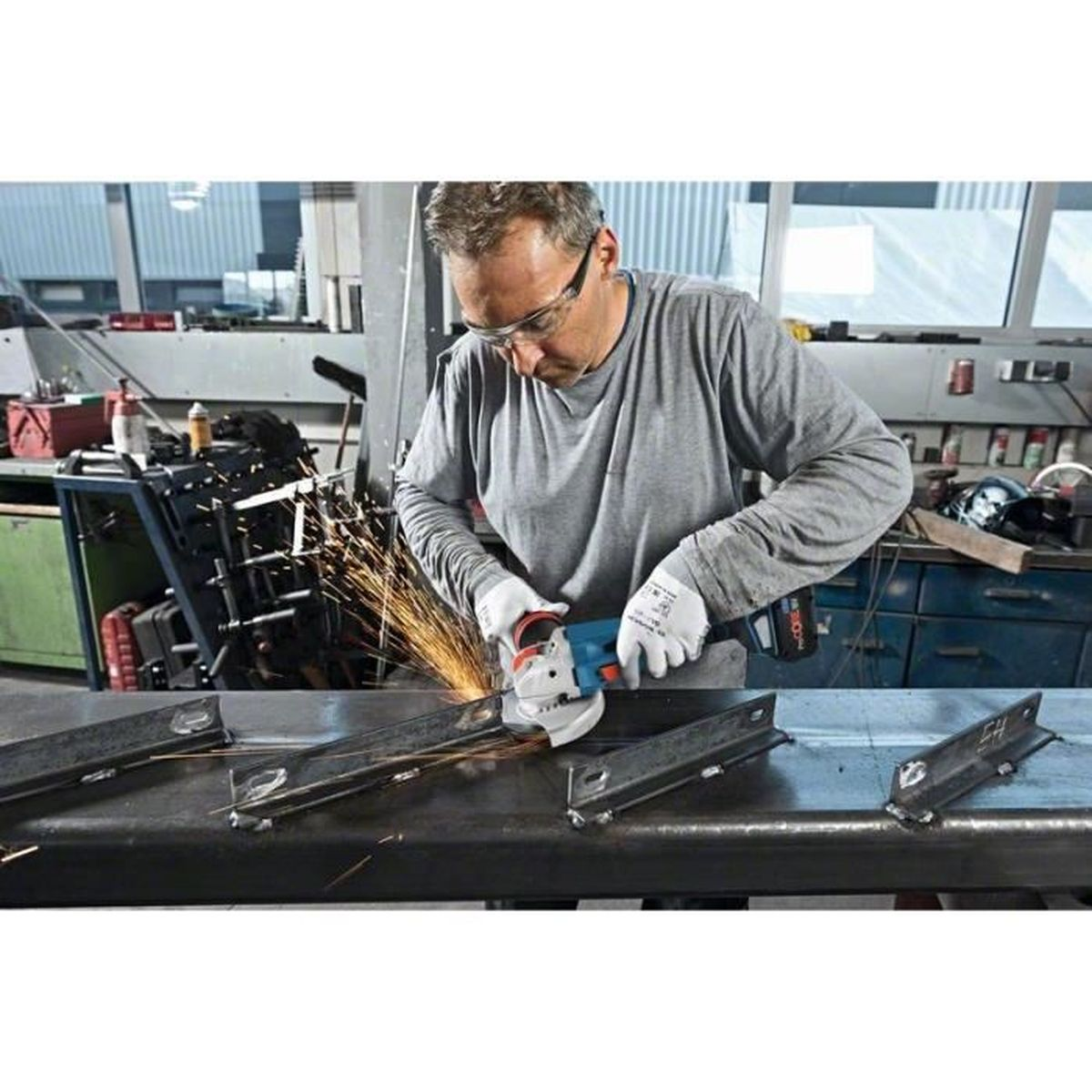 Mężczyzna szlifuje metal szlifierką kątową, lecą iskry.