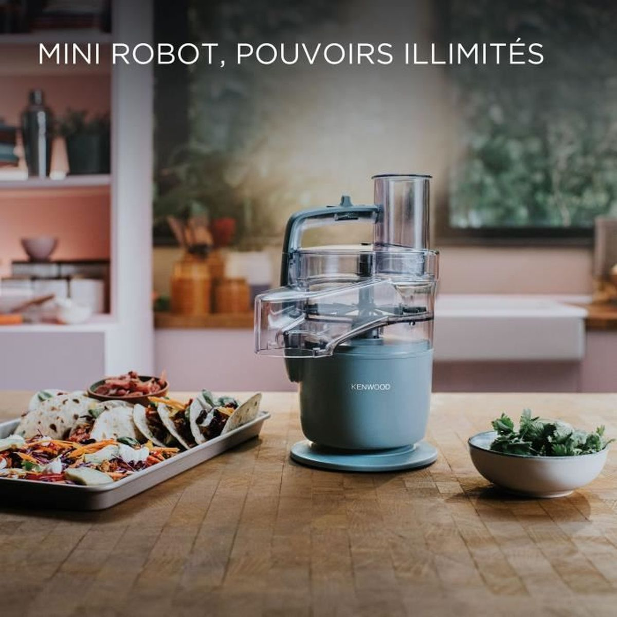 Un robot da cucina Kenwood azzurro su tavolo di legno vicino a tacos e coriandolo.