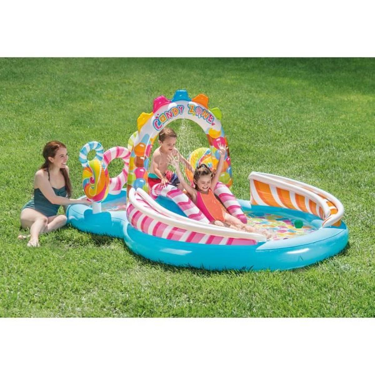 Piscina gonfiabile con scivolo e due bambini, una donna seduta accanto.